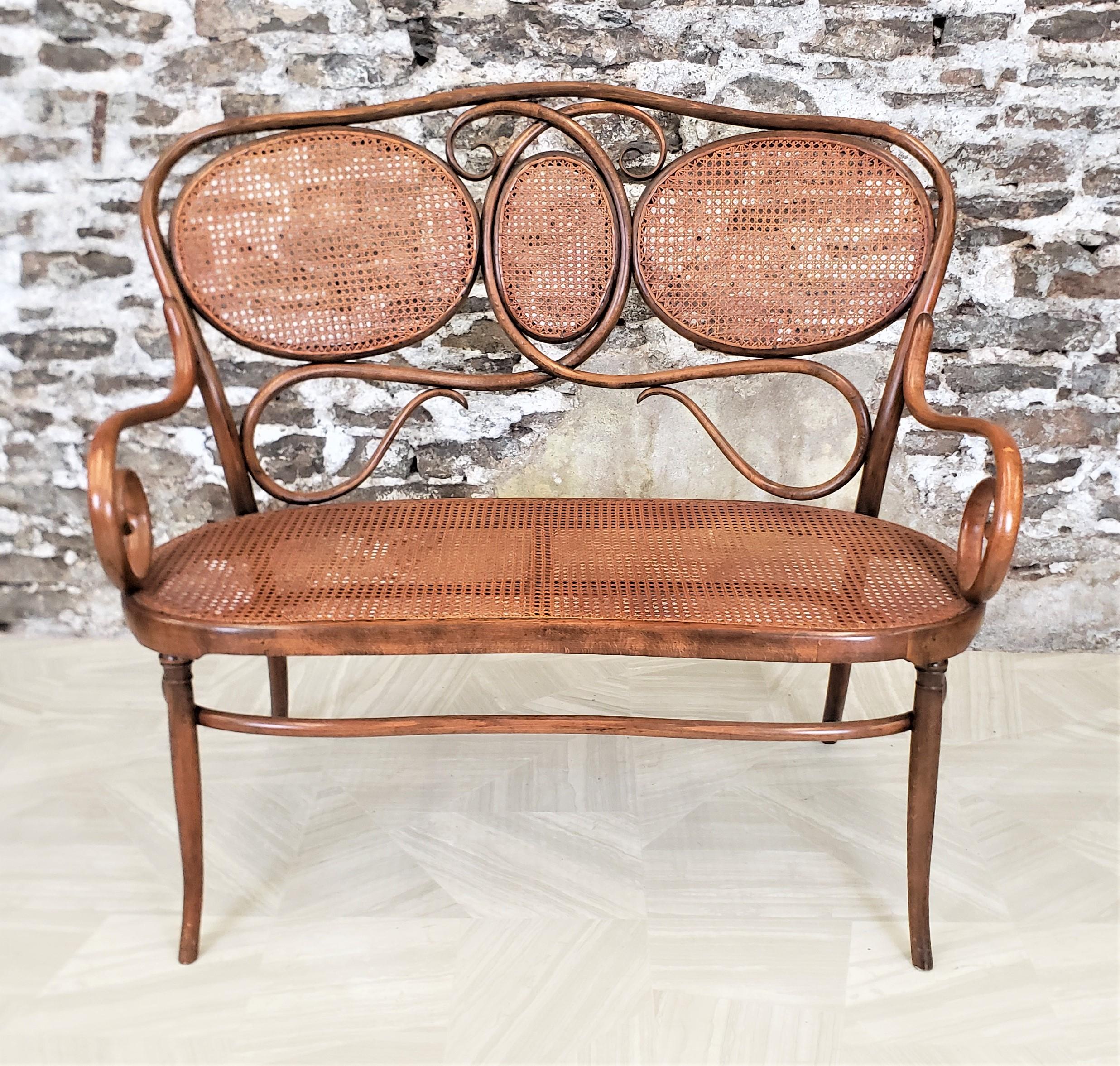 This antique bentwood settee or loveseat is unsigned, but being attributed to Gebruder Thonet based on the materials and design, and as such originates from Vienna, Austria and dates to approximately 1890 and done in the period Art Nova style. The