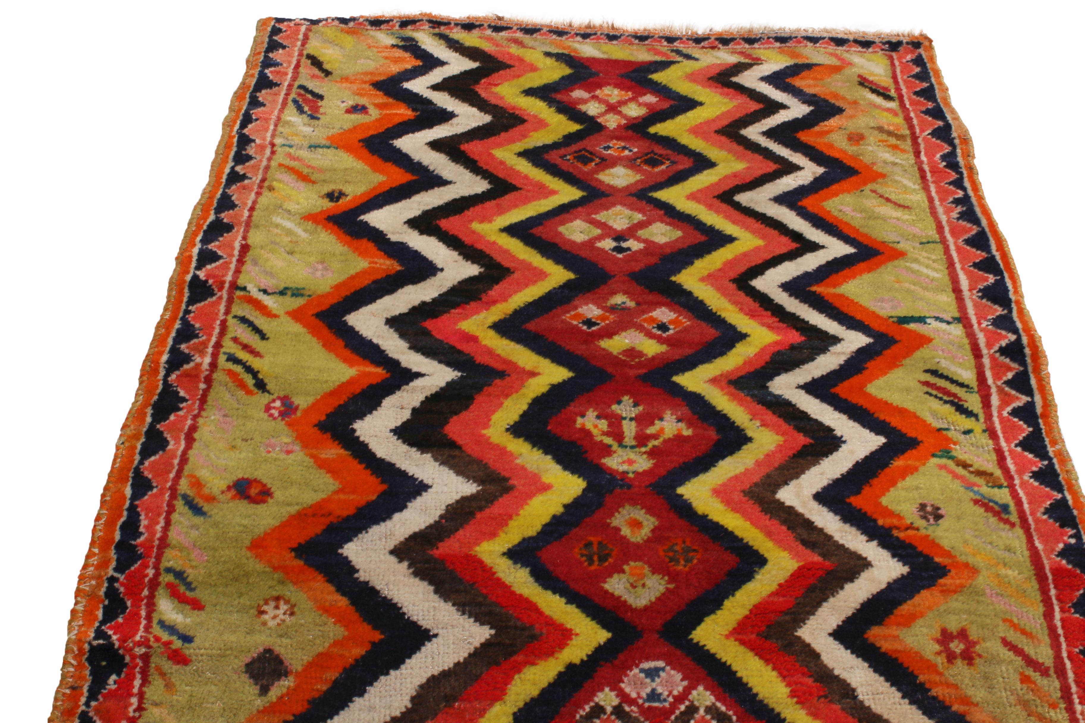 Originating from Persia between 1900-1910, this antique hand knotted Gabbeh wool rug hosts a unique variety of unfolding sawtooth and artwork borders, complementing the Chevron field pattern with a unique array of tribal. Green, red, orange, yellow,