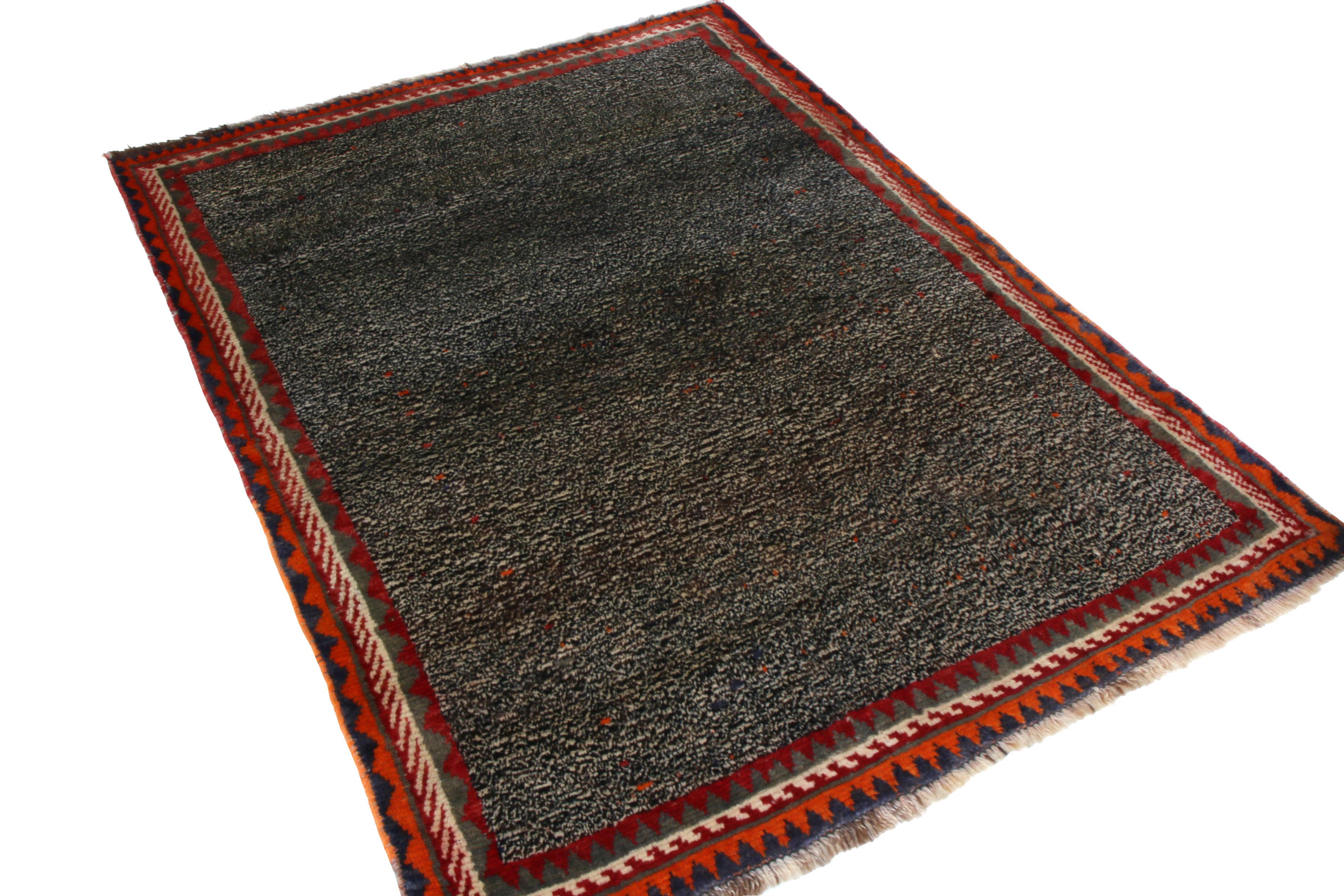 Made with hand knotted wool originating between 1910-1920, this antique Gabbeh Persian rug enjoys the tactful juxtaposition of a tribal geometric border with a more granular, subtle all-over field design, likewise a play of the vibrant red and