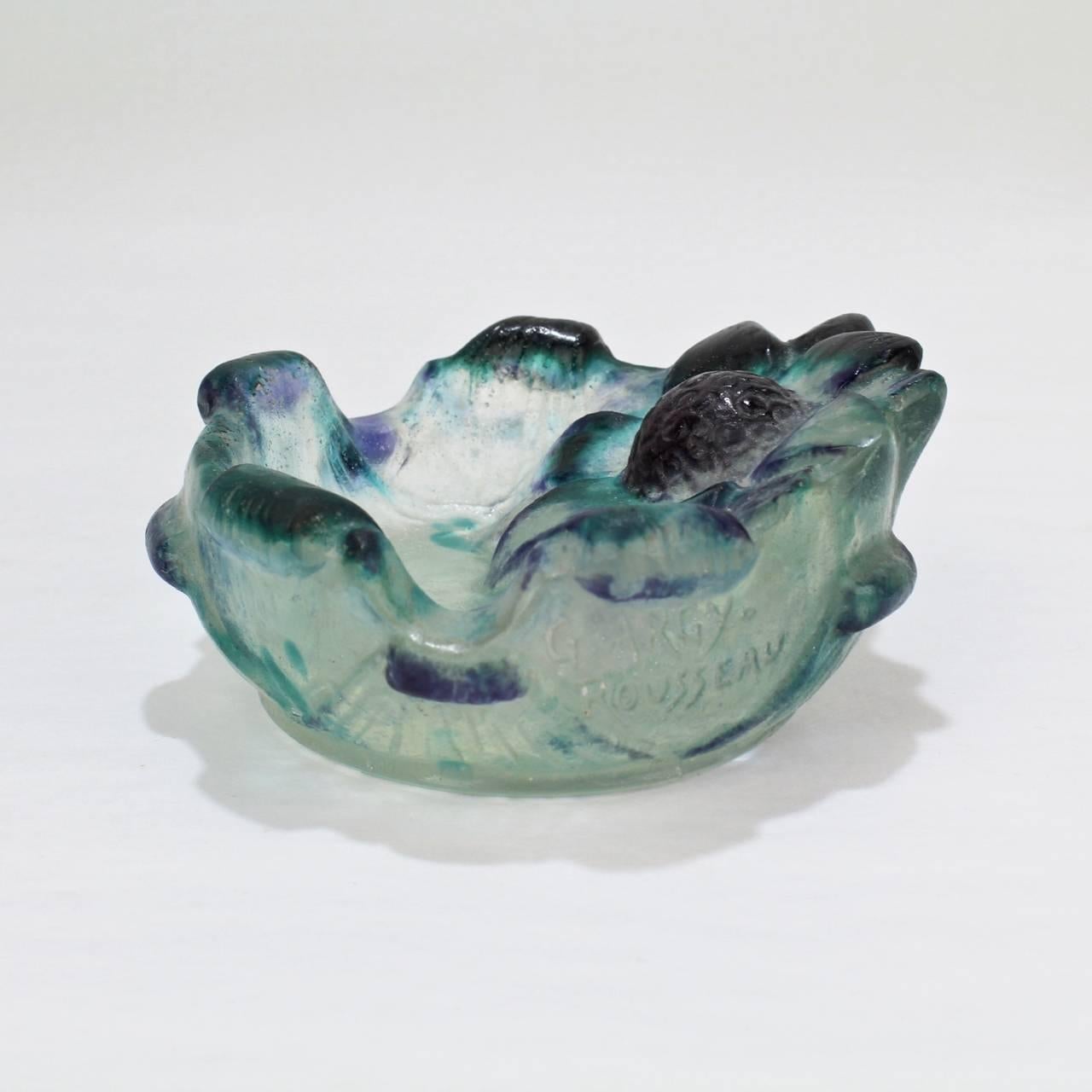 A very fine Gabriel Argy-Rousseau pate-de-verre art glass ashtray.

The floriform base has notched sides and a figural sunflower or daisy flower head centered on the rim. The glass has blue and green inclusions and bears an impressed G.