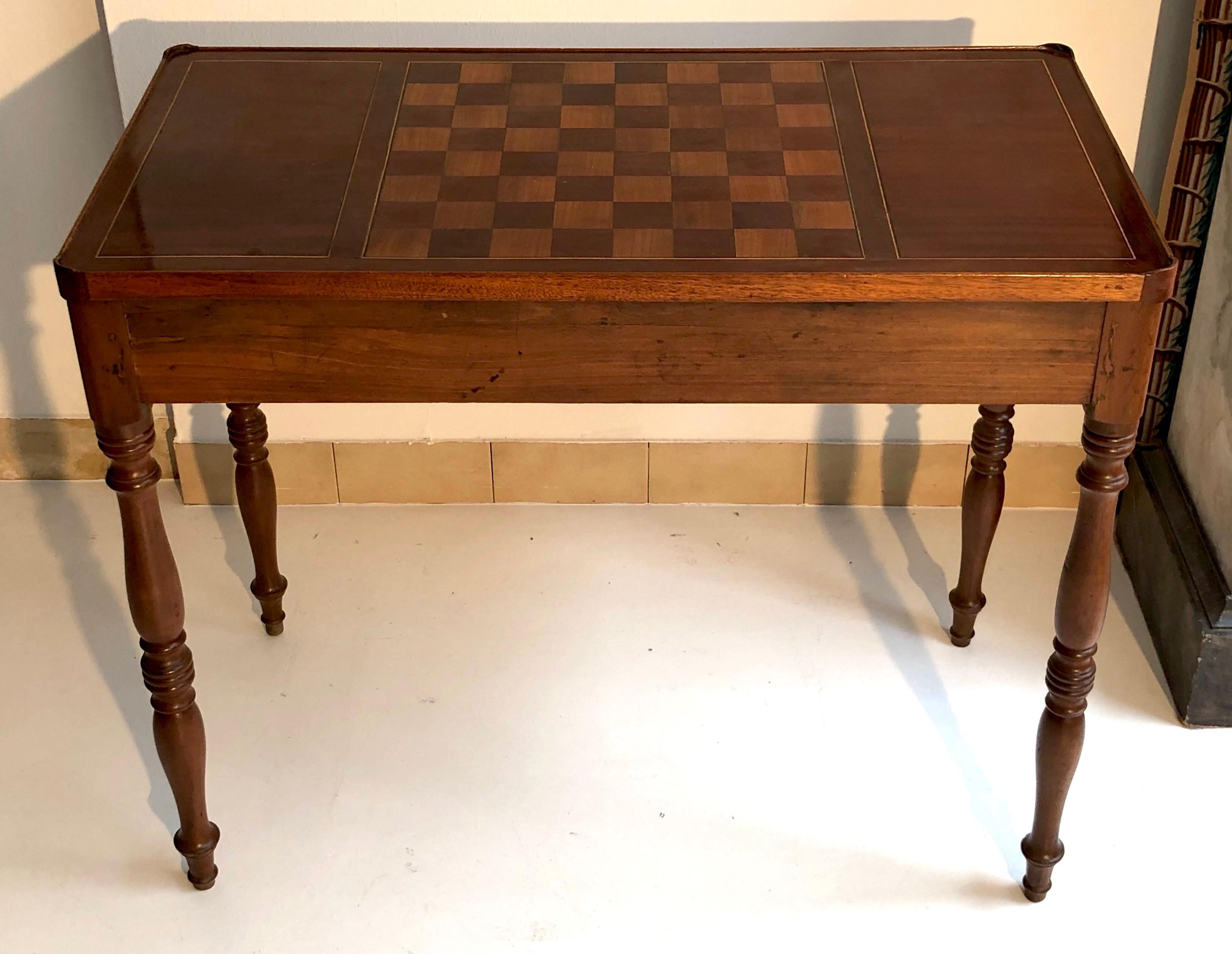 This game table is convertible into a chessboard, a tric trac board for backgammon, checkers and it also doubles as a writing desk. The writing side of the table is covered with gold embossed light brown cow leather. This charming piece of furniture