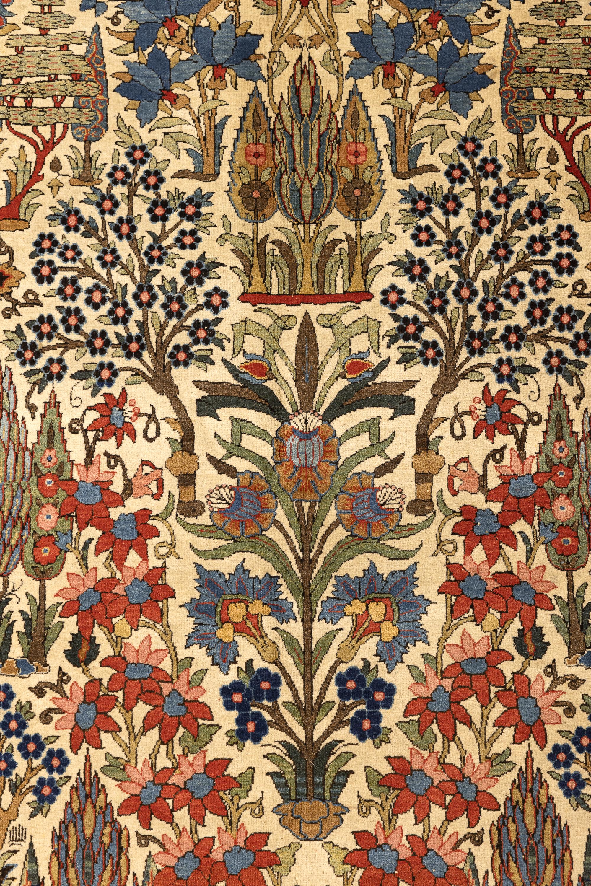 Ce tapis ancien présente une remarquable composition inspirée des jardins, se déployant sur un champ ivoire rempli de fleurs stylisées, de branches feuillues, de cyprès, d'arbustes et d'arbres en fleurs. Le design est organisé selon une disposition