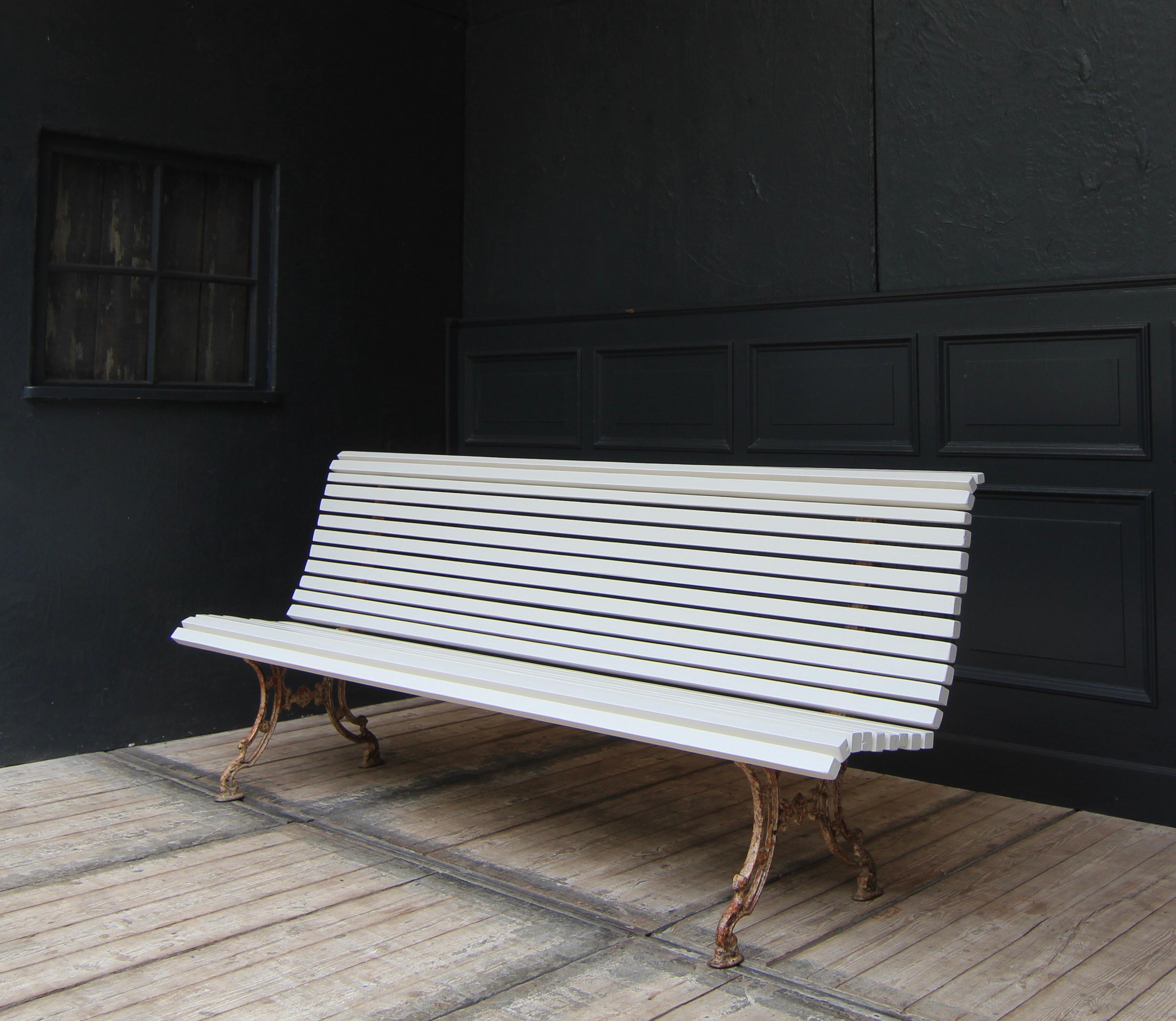Beautiful antique park bench or garden bench with cast-iron feet from around 1900.

The pine wood slats are painted creamy white. The cast iron has been carefully cleaned of flaking paint and rust film and then sealed with a transparent