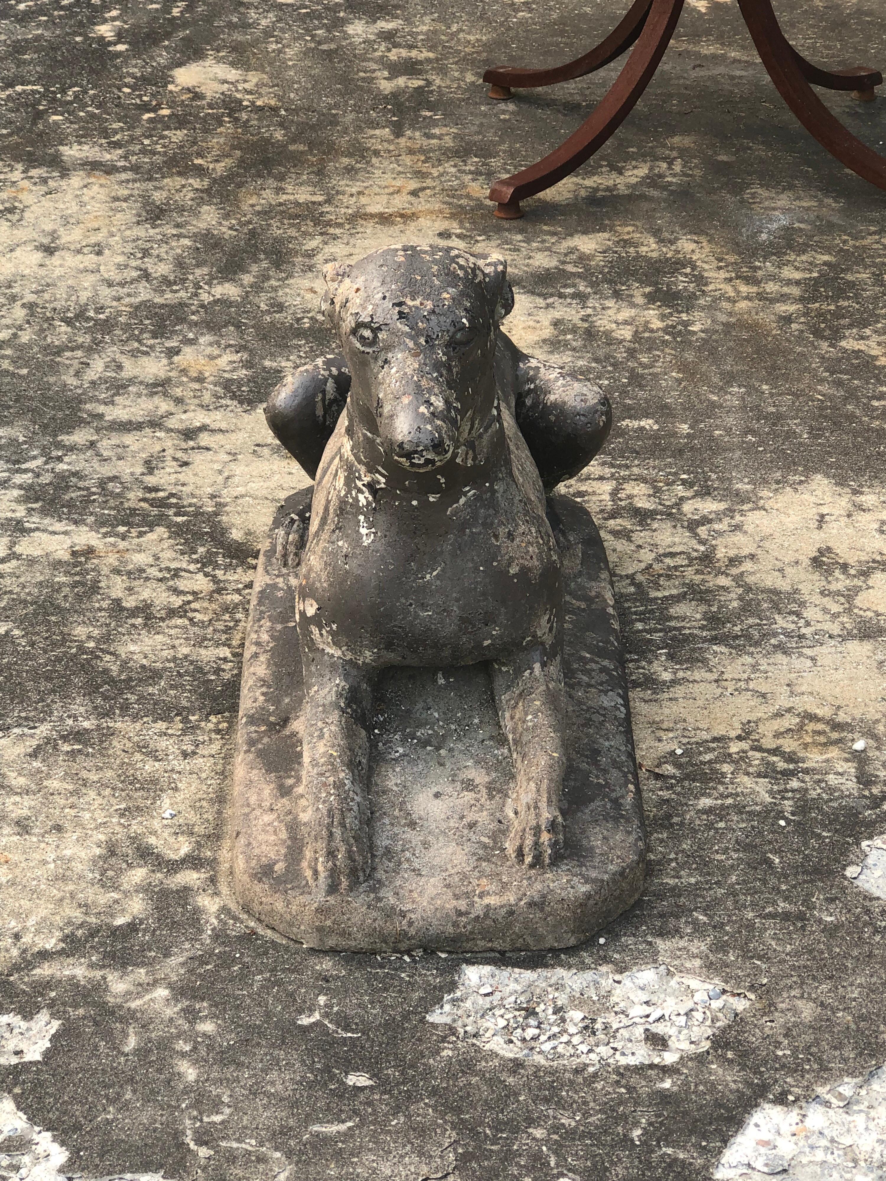 Antique garden statue of a dog. It looks to be a greyhound or whippet. Nice weathered patina with a bit of gray worn paint over cement. The dog is wearing a thick collar. No breaks or cracks.

