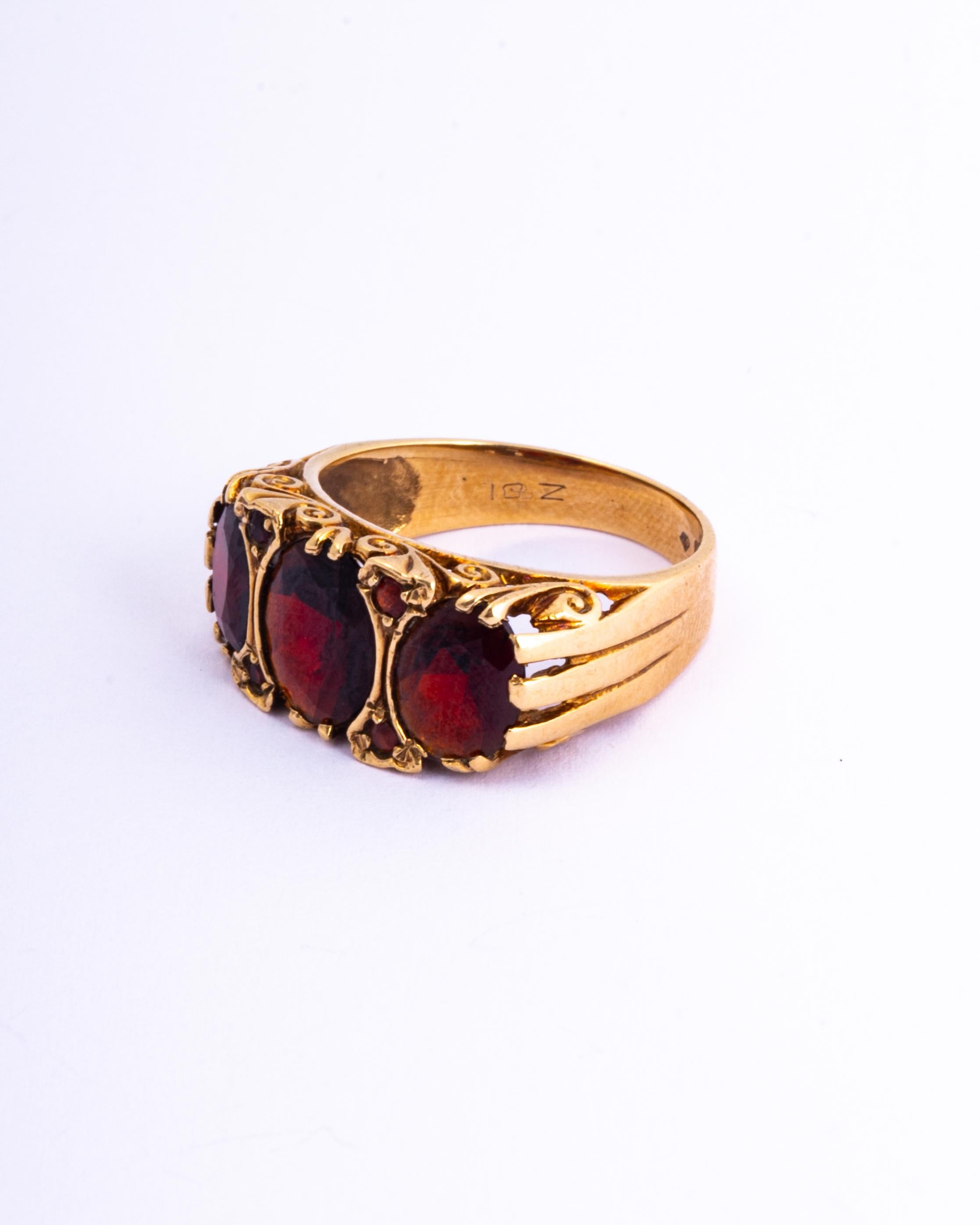 The garnet stones in this ring are deep red in colour and when they hit the sunlight they glow bright red. Either side of the central stone there are pairs of smaller garnets. The gallery is open and has scroll detail. 

Ring Size: O 1/2 or 7 1/2