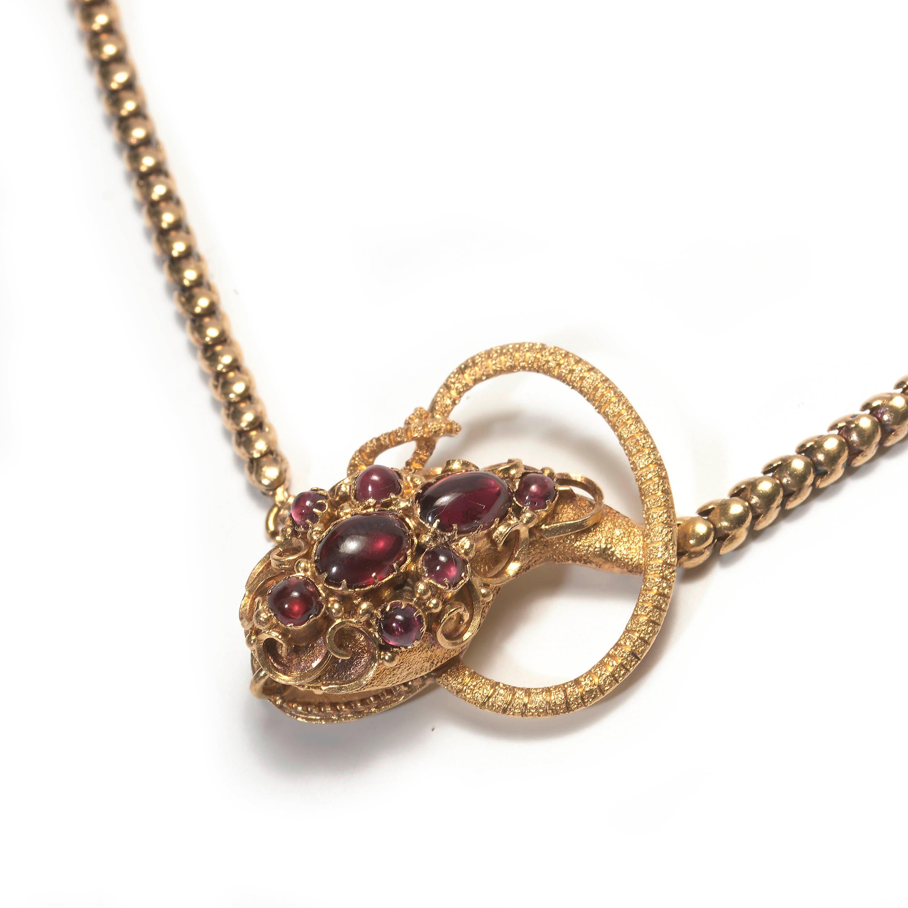 An early Victorian snake necklace, with eight cabochon-cut garnets set in the head, in closed back claw settings, surrounded by scrolling wirework, the mouth is open, with pointed teeth, with a tapering, articulated scale ring link body and an