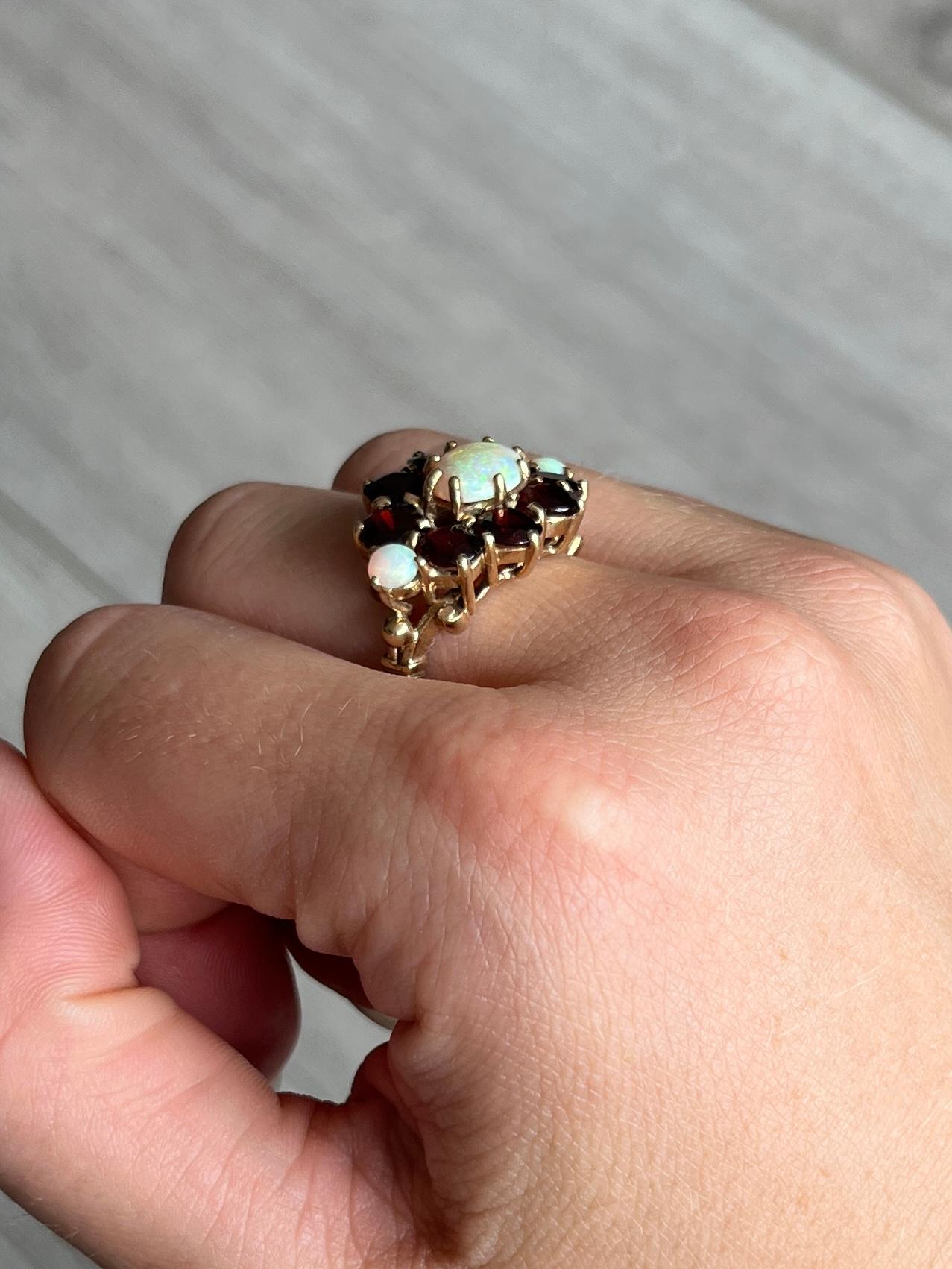 This striking ring holds round cut garnets totalling approx 4ct and 3 shimmering opals. All the stones sit in 9carat gold claws. Hallmarked London 1975.

Ring Size: N or 6 3/4 
Cluster Dimensions: 16x25mm
Height Off Finger: 7mm

Weight: 6.7g