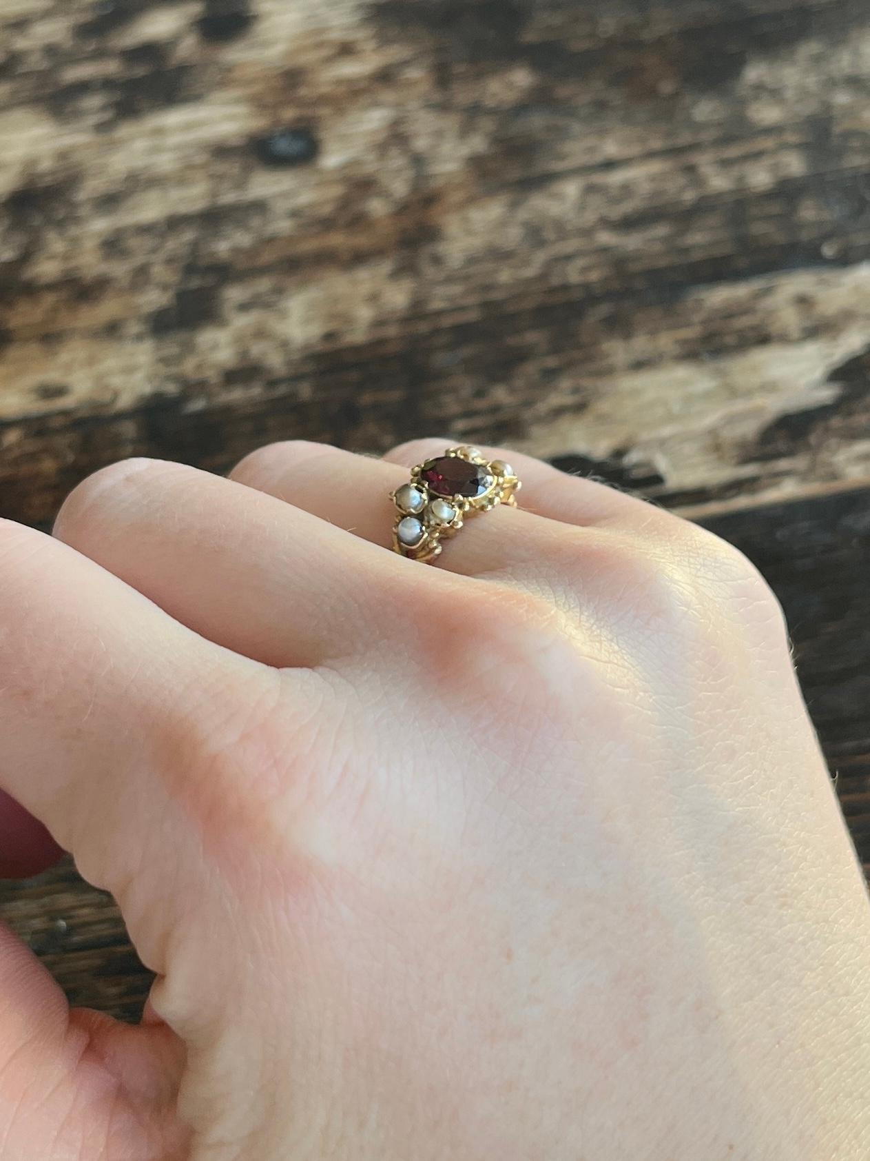 The garnet at the centre of the ring measures 1ct and there are three pearls set each side. The ring is modelled in 9 carat gold and is very decorative. 

Ring Size: L or 5 3/4 
Face Width: 9mm

Weight: 2.1g