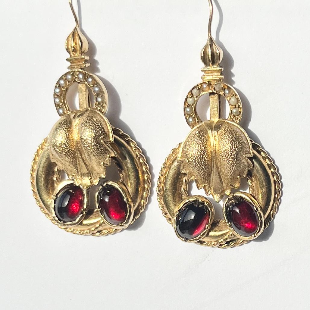 These gorgeous earrings hold smooth and glossy garnet stones set in 9carat gold and also hold seed pearls. Fully hallmarked London 1890.

Drop from ear: 4cm
Stone Dimensions: 5x7mm

Weight: 9.2g