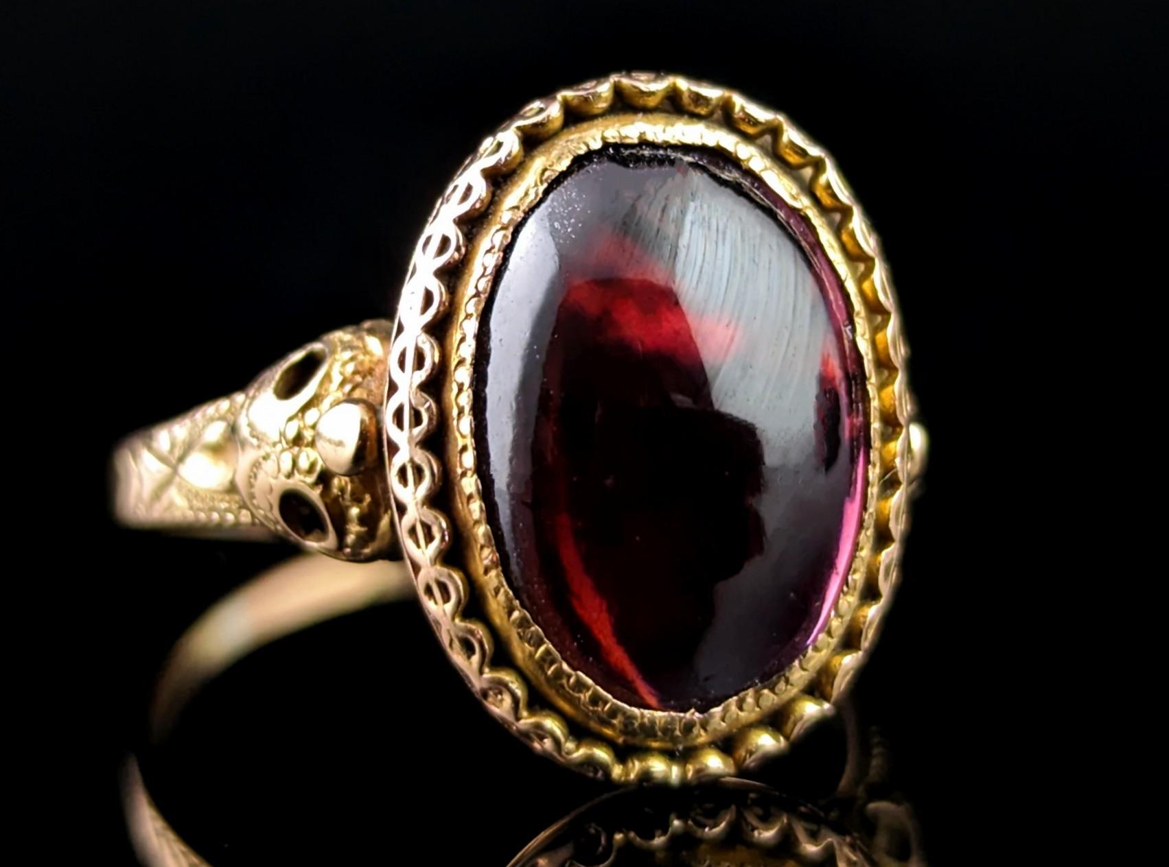 This handsome antique 18ct gold Garnet cabochon ring has a little hidden secret.

Those magnificently designed shoulders feature a bird mask design, very unique and surely a specially commissioned piece.

When turned on its side you can see the