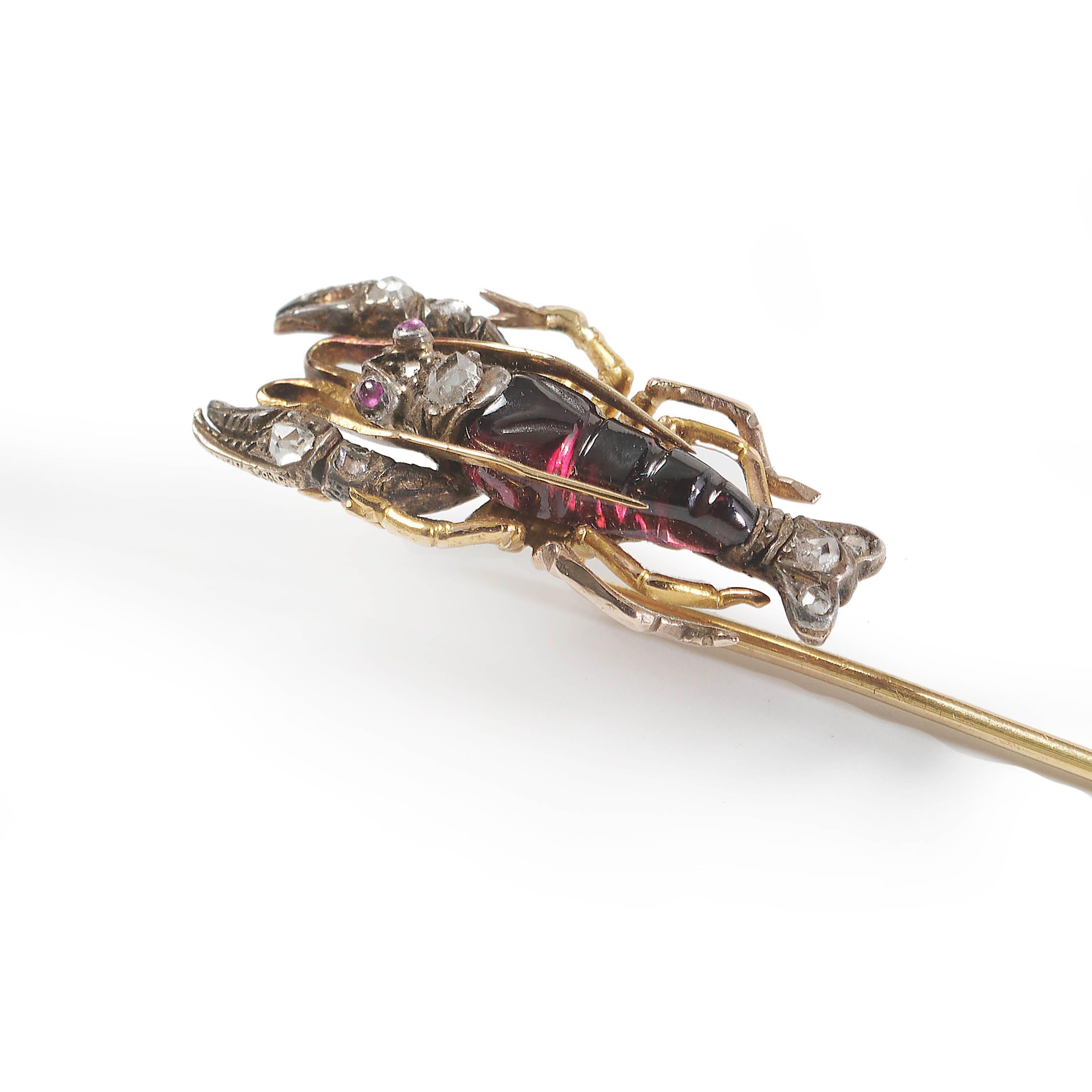 A Victorian lobster tie pin, hat pin or stick pin, with the body of the lobster carved from a single piece of garnet, with rose-cut diamonds set in the claws head and tail fins, with cabochon ruby set eyes, in silver grain settings, mounted in gold,