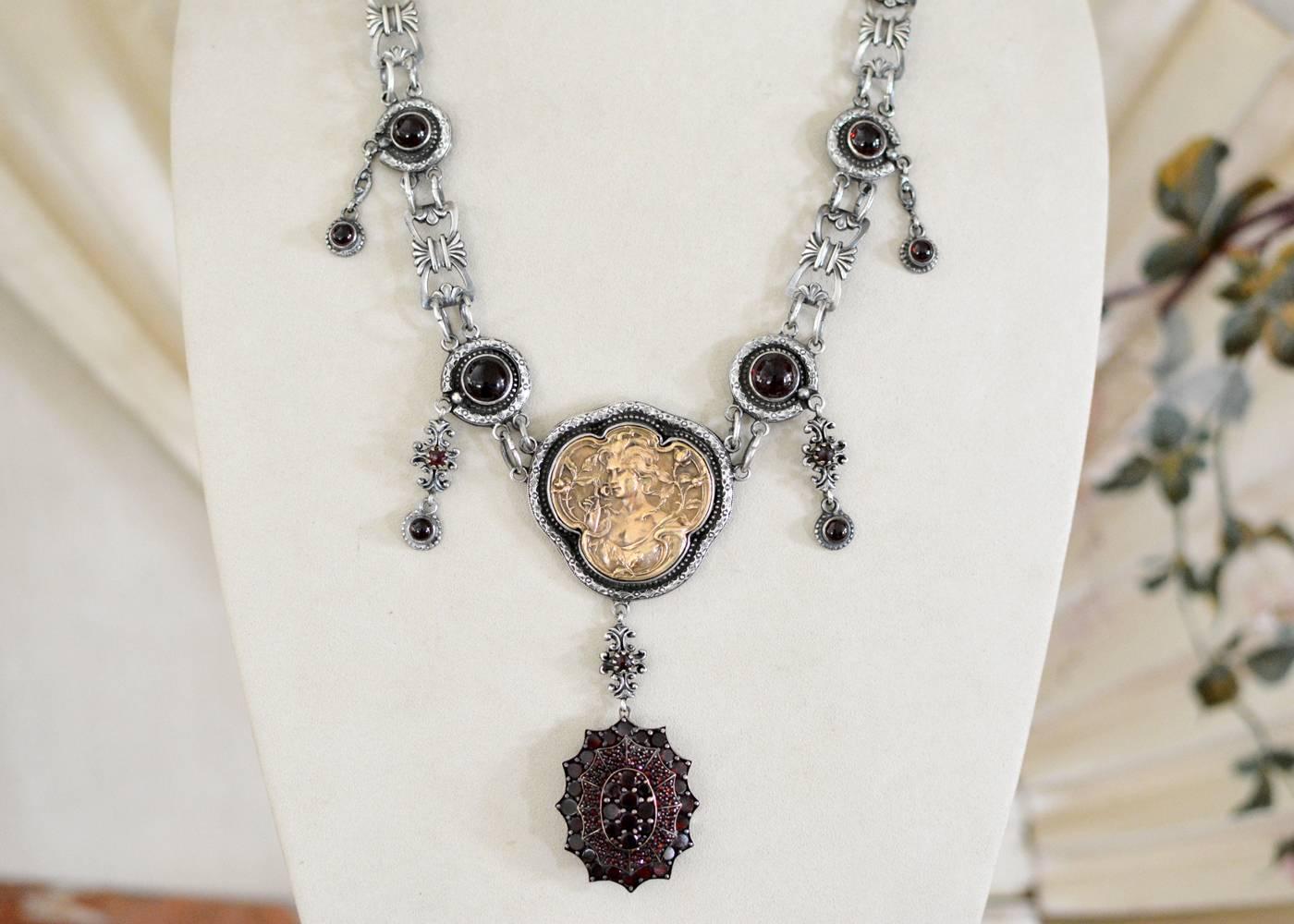 This one of a kind drop necklace features a large antique Victorian Rose Cut Garnet period locket hanging gracefully from a bronze Goddess medallion on a rose cut garnet festoon. Each antique figural link connects natural garnet cabochons, bezel