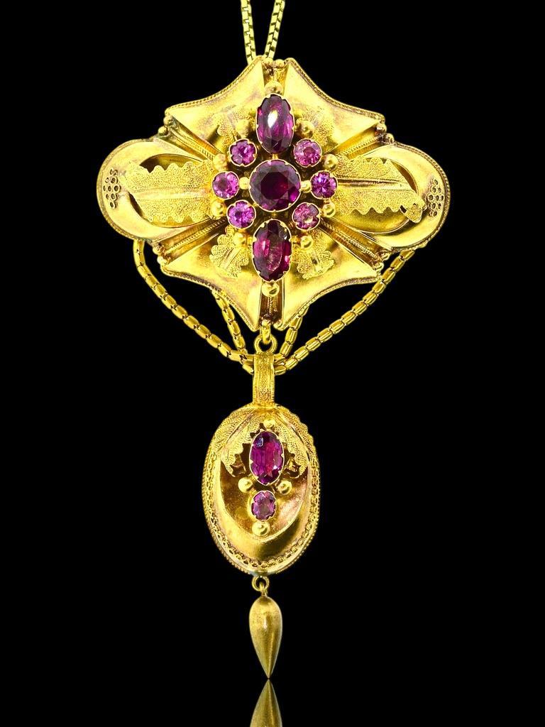 Antique, American Civil War era, yellow gold pendant/brooch with stylized leaf motifs that appear to open up revealing at the center a cluster of natural vivid pink/red Almandine garnets. Both round and oval cut, these stones are set in classic