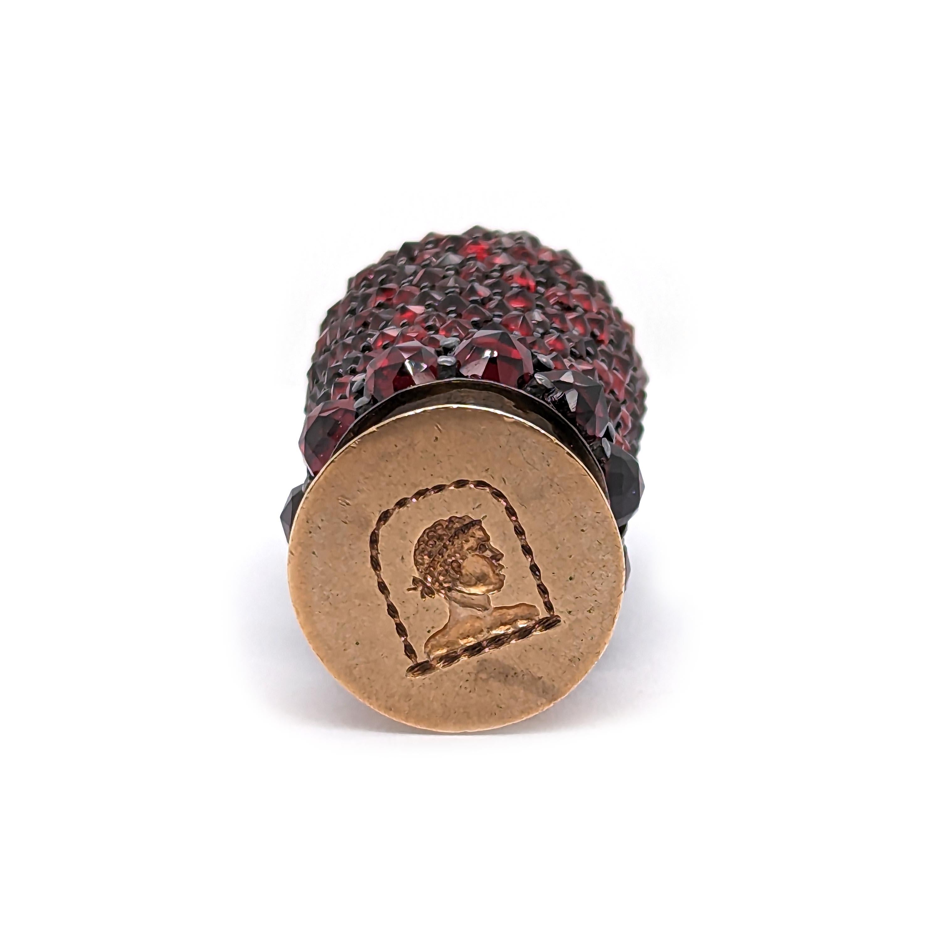 An antique garnet set desk seal, with pavé set rose-cut garnets on the handle, mounted in silver, with a gold seal, engraved with the head of a man, with a Roman hairstyle, circa 1850.

