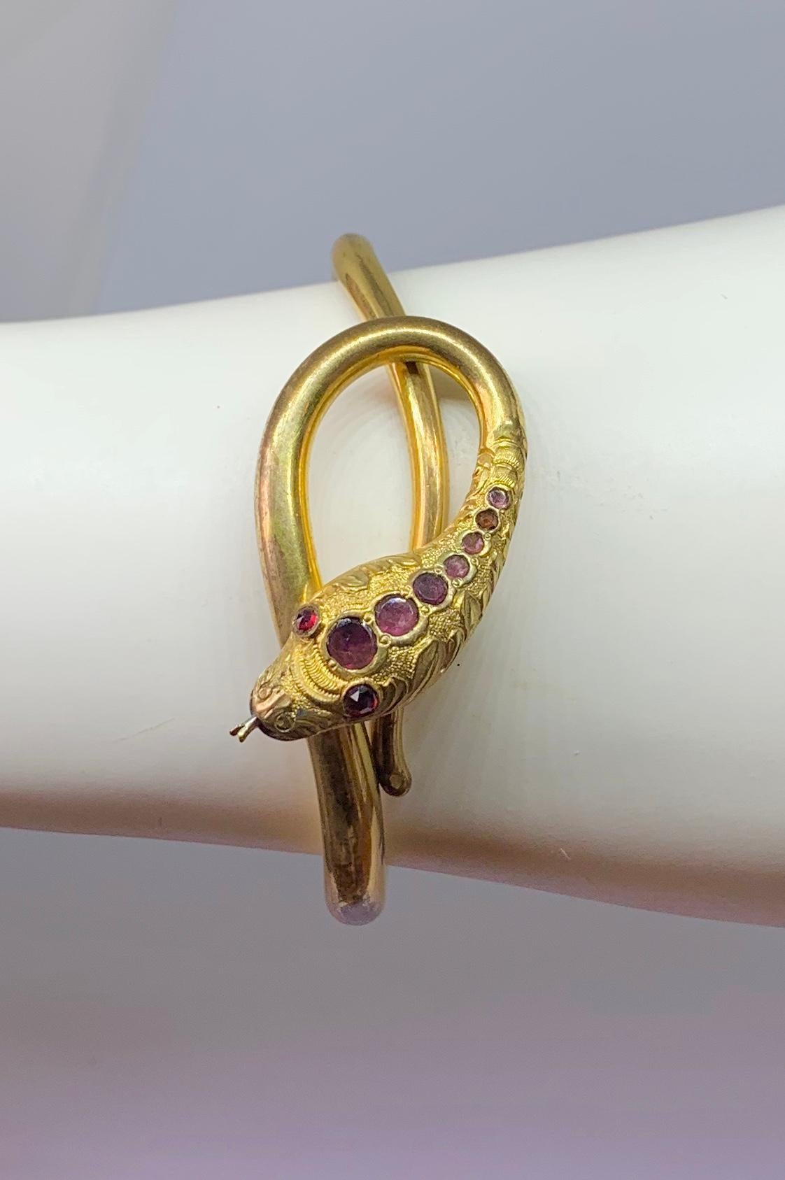 This is a very rare and wonderful antique Victorian Coiled Snake Bracelet with beautiful Bohemian Garnets set in the head and eyes dating to circa 1830-1870.  The bangle bracelet is gold filled.  Designed as three articulated sections, the bangle