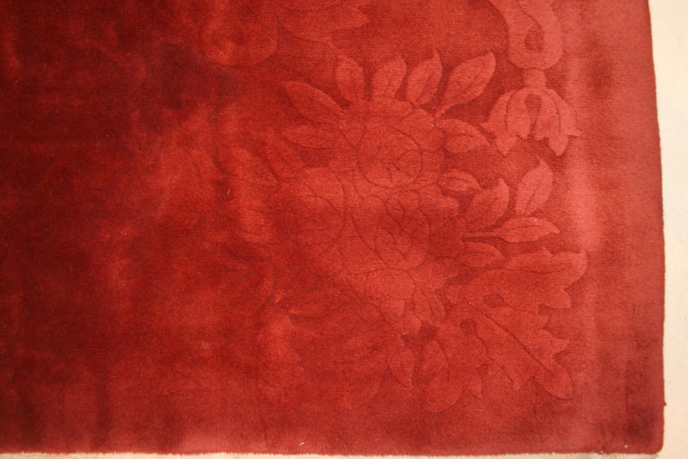A unique Art Deco carpet distinguished by a sparse and subtle floral tone-on-tone pattern in shades of garnet and amaranth. Rugs of this type were commissioned by Nichols & Co. in Tianjin and were often designed by American artists of the period.