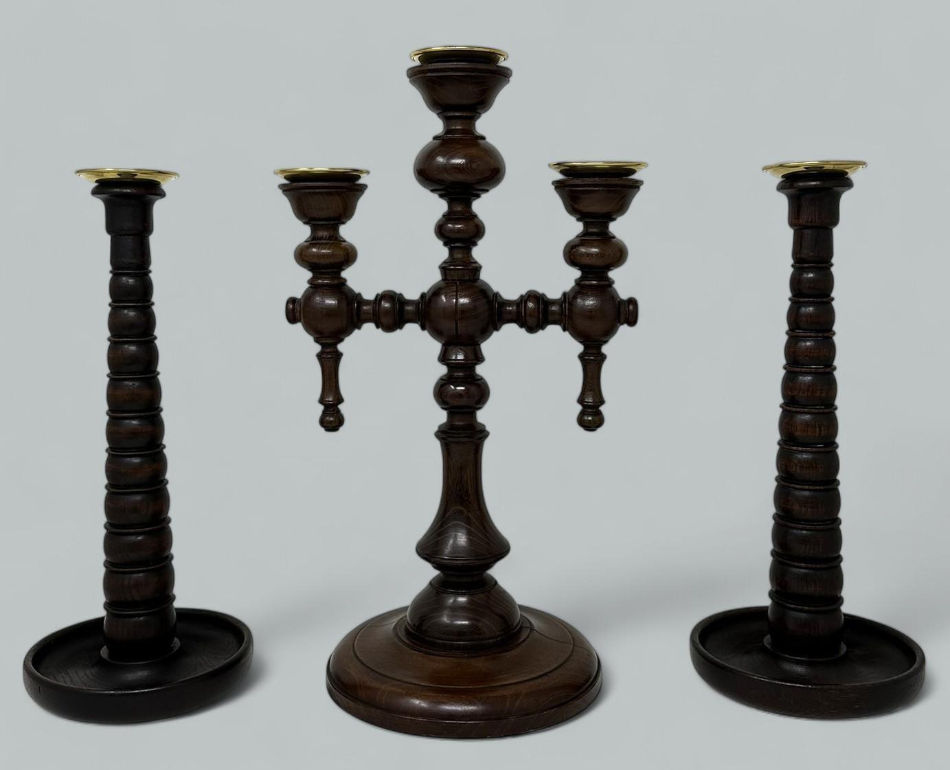 Garniture exceptionnellement élégante de chandeliers en chêne poli de la fin de l'époque victorienne, comprenant un candélabre à trois lumières et une paire de chandeliers à une lumière d'origine anglaise, accompagnés de leurs plateaux d'égouttage