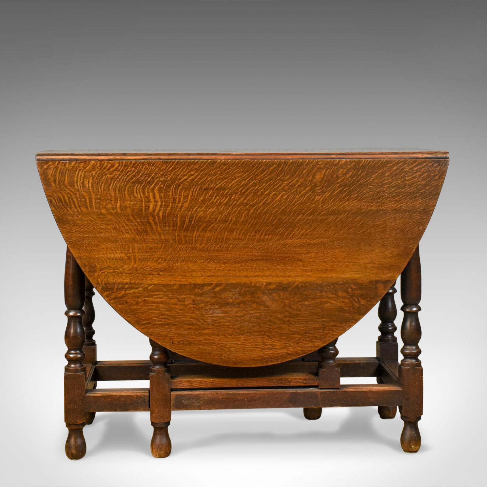This is an antique gate leg table, an Edwardian, English, oak, country kitchen dining table in the 17th century taste, dating to circa 1910.

Crafted from generously thick English oak
Grain interest displaying wisps of medullary rays
Good color