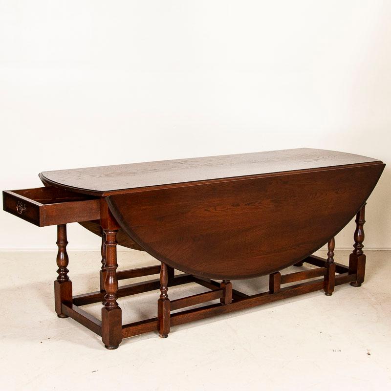This attractive gateleg dining table is also known as an English wake table with drop leaves. Notice the deep patina of the dark oak, aged and naturally distressed over generations of use and the 2 narrow drawers, one on each end of the table. The