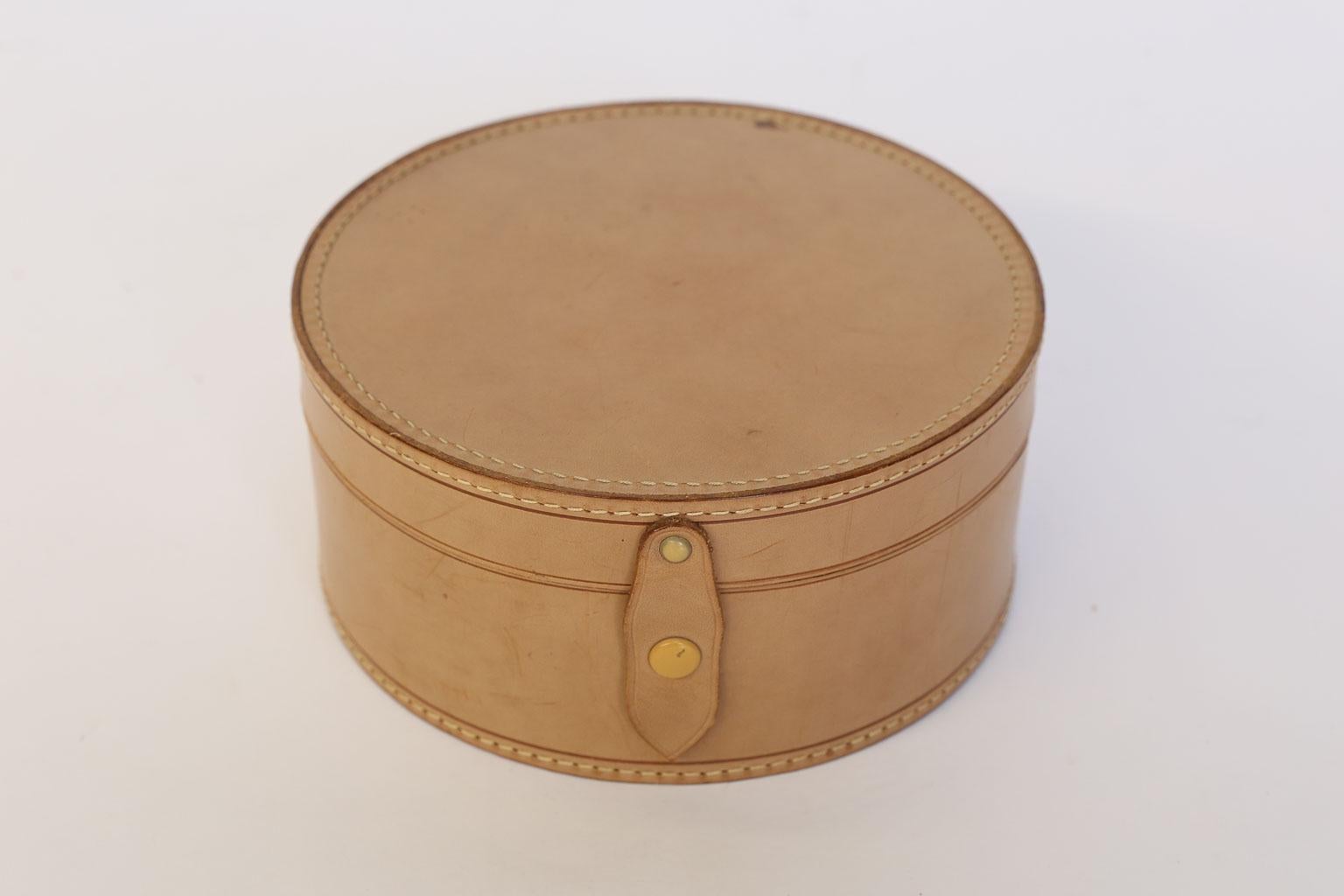 This is a beautiful leather gentleman's collar box. The lovely round shape of the box makes it a unique accessory for your dresser or bookshelf. The leather exterior and linen interior are in near perfect condition. The snap on the leather tab is