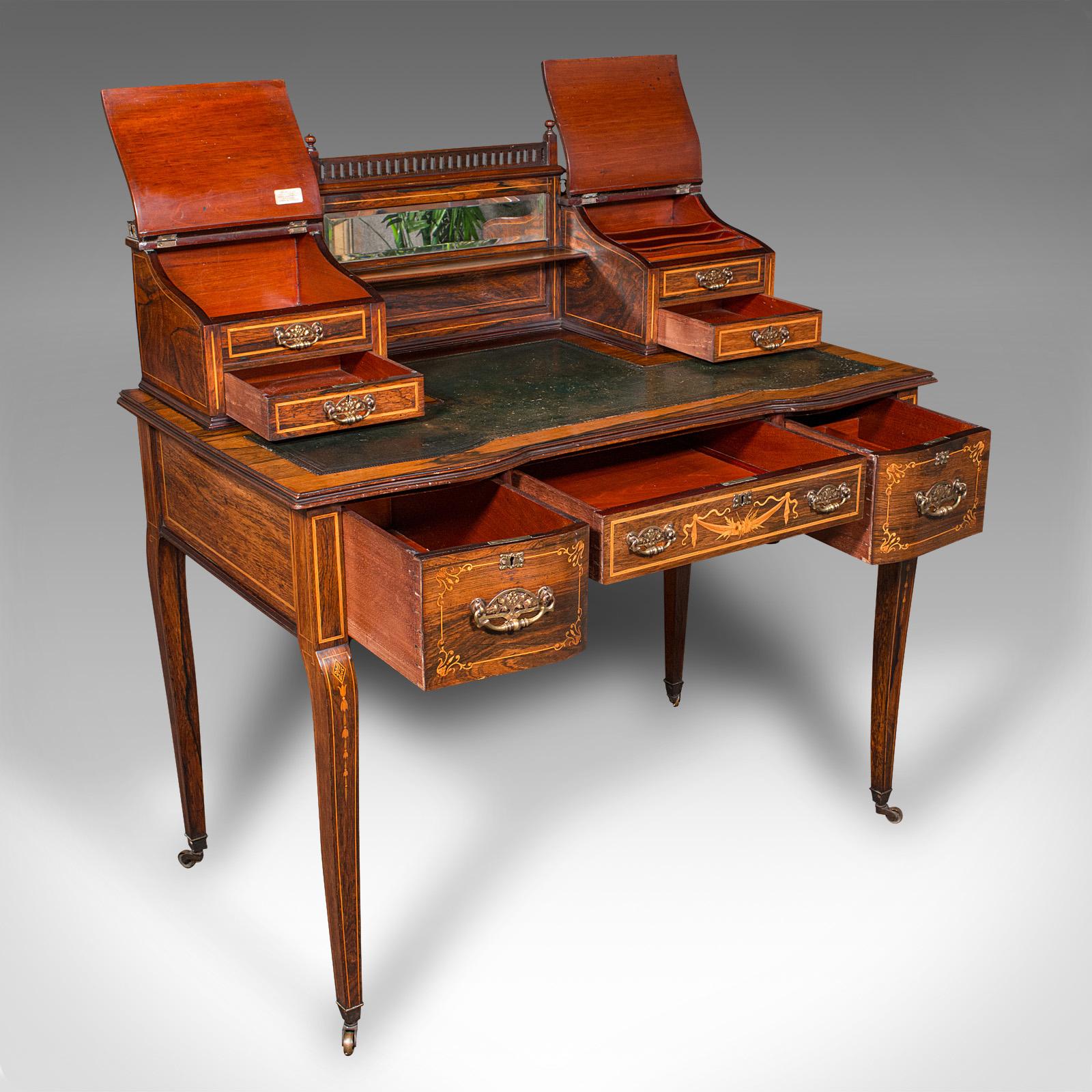 This is a fine antique gentleman's correspondence desk. An English, rosewood writing table with decorative boxwood inlay, dating to the late Victorian period, circa 1900. Rich in detail and craftsmanship, with versatile storage and a graceful
