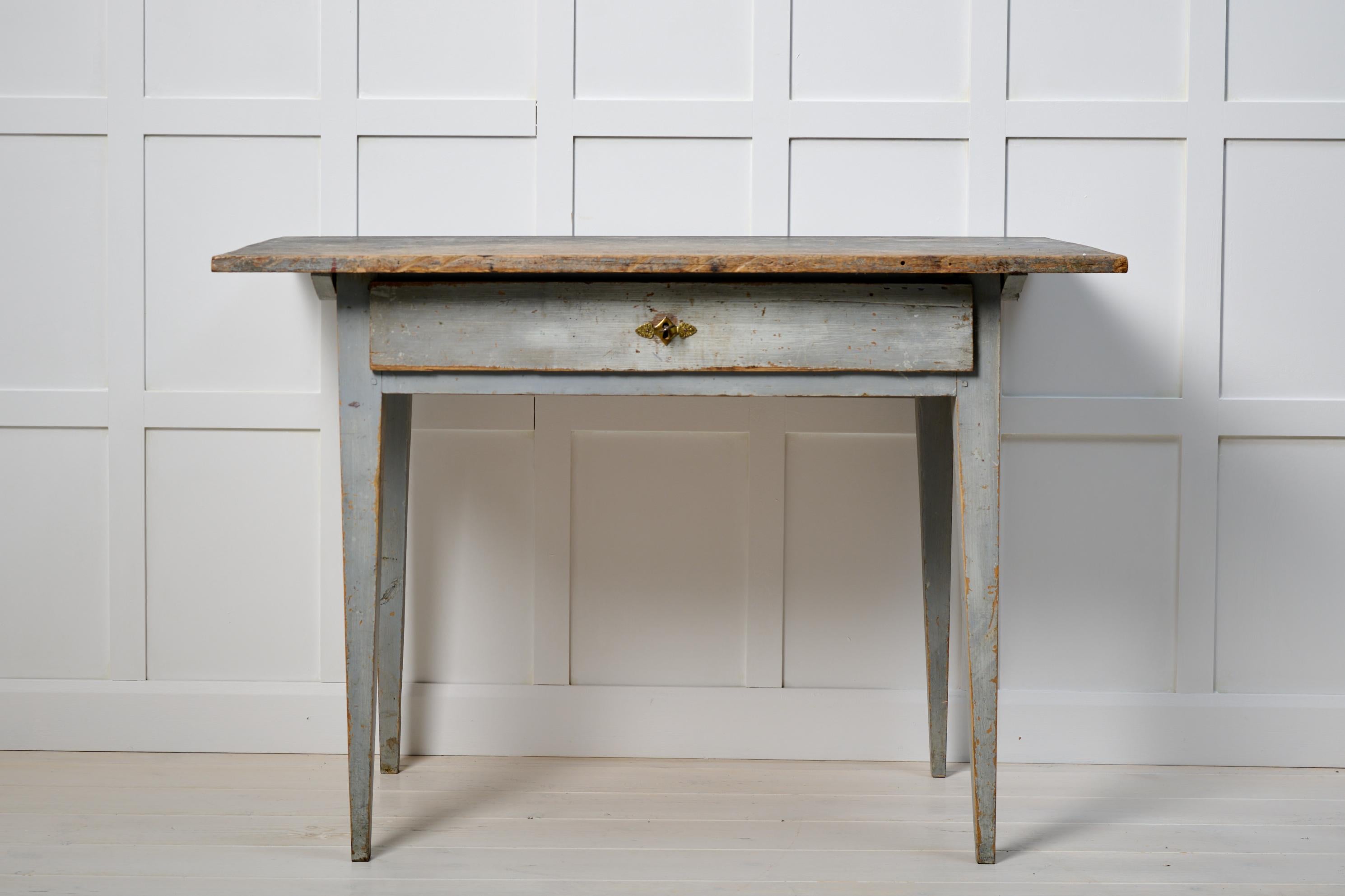 Genuine antique Swedish table in gustavian style. This side or wall table is a genuine northern Swedish country house furniture from 1810 to 1820. Made in solid pine with straight tapered legs. A functional drawer with old hardware in brass and