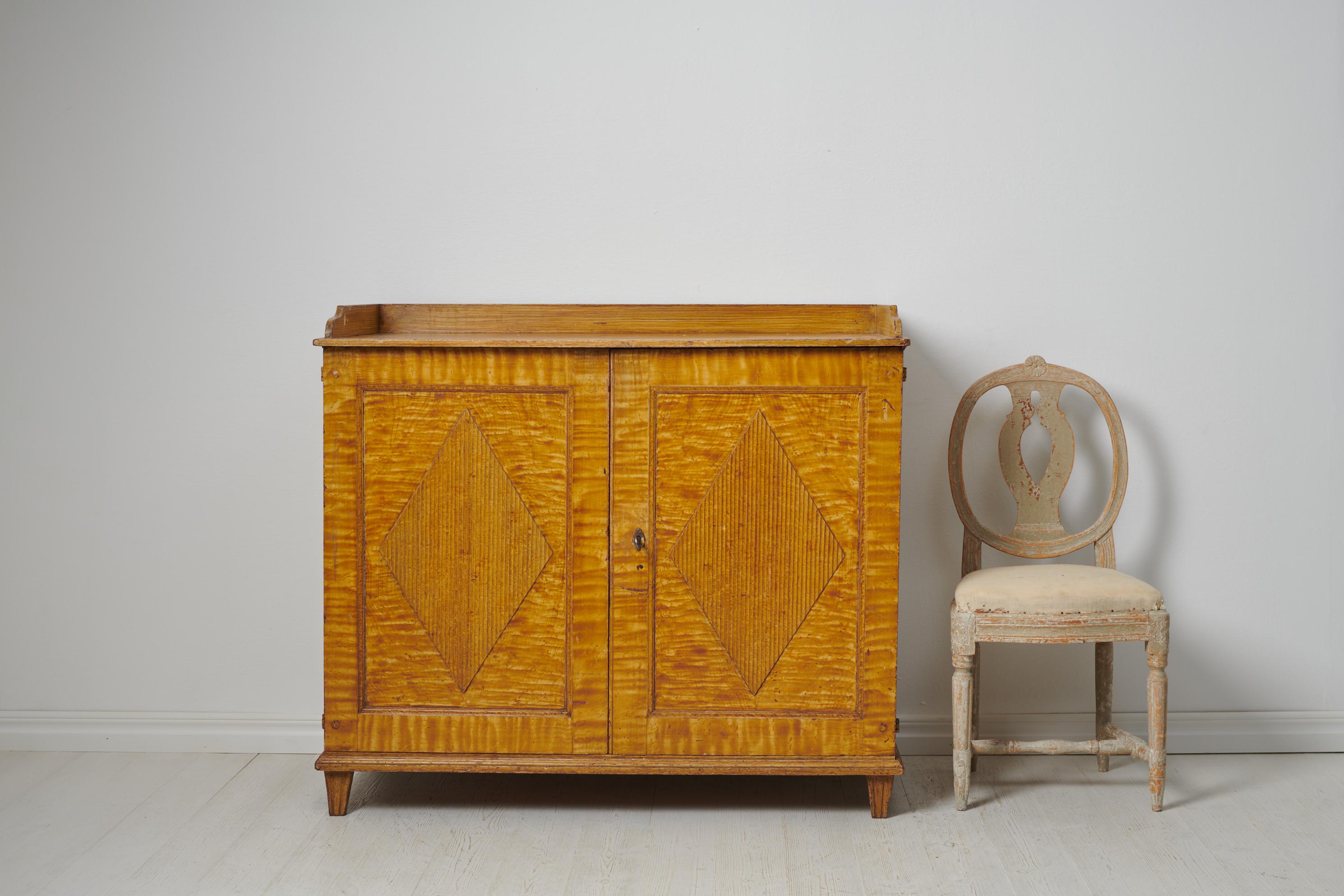 Genuine Swedish gustavian sideboard made during the first few years of the 19th century, around 1810. The sideboard is made by hand in solid Swedish pine. The double doors are decorated with fluted diamonds and the frame stands on straight tapered