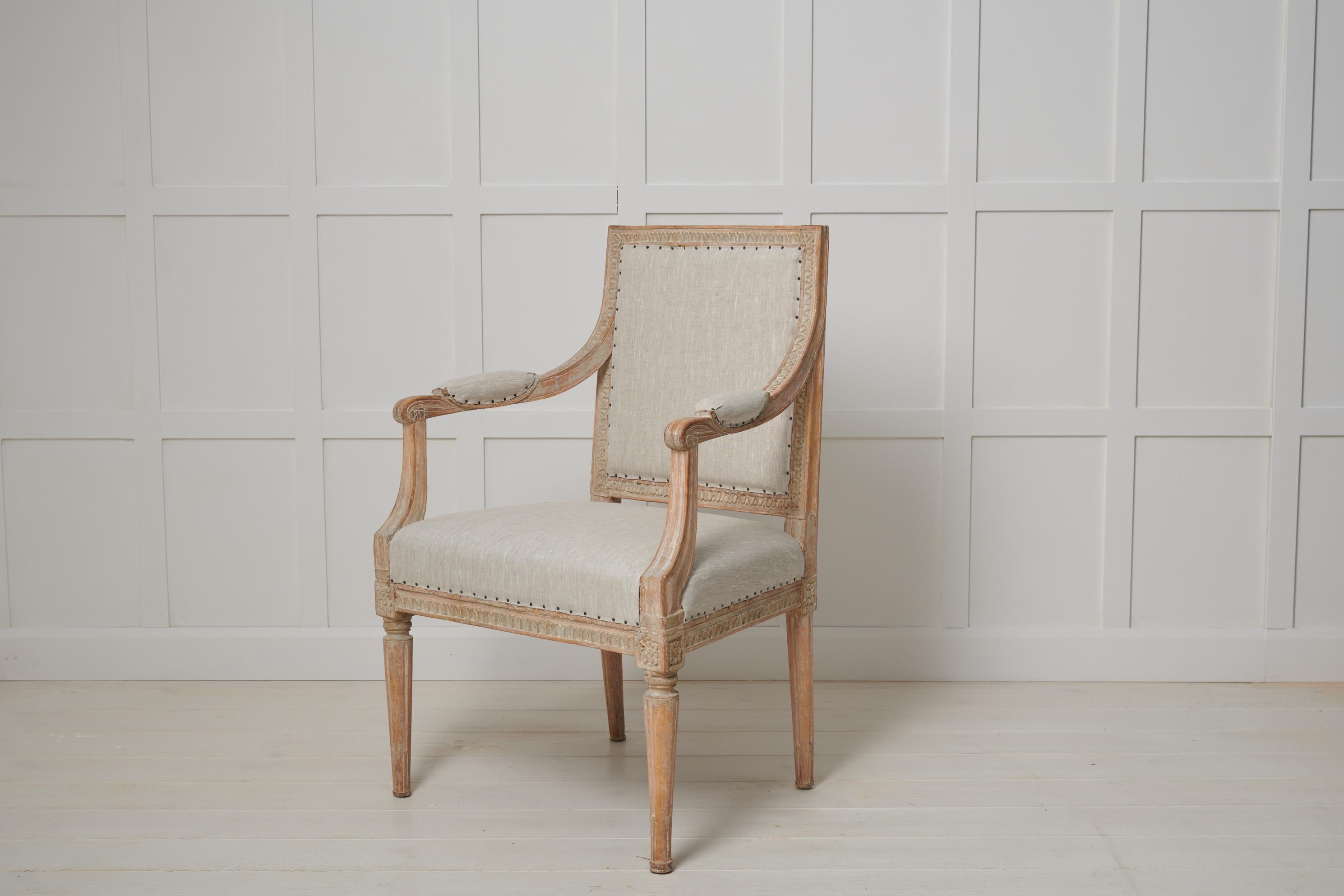 Swedish gustavian upholstered armchair from the late 18th century, circa 1790. The armchair has a straight shape with hand carved wooden decorations all over the chair. The decor spans around the backrest, down the armrest and around the seat