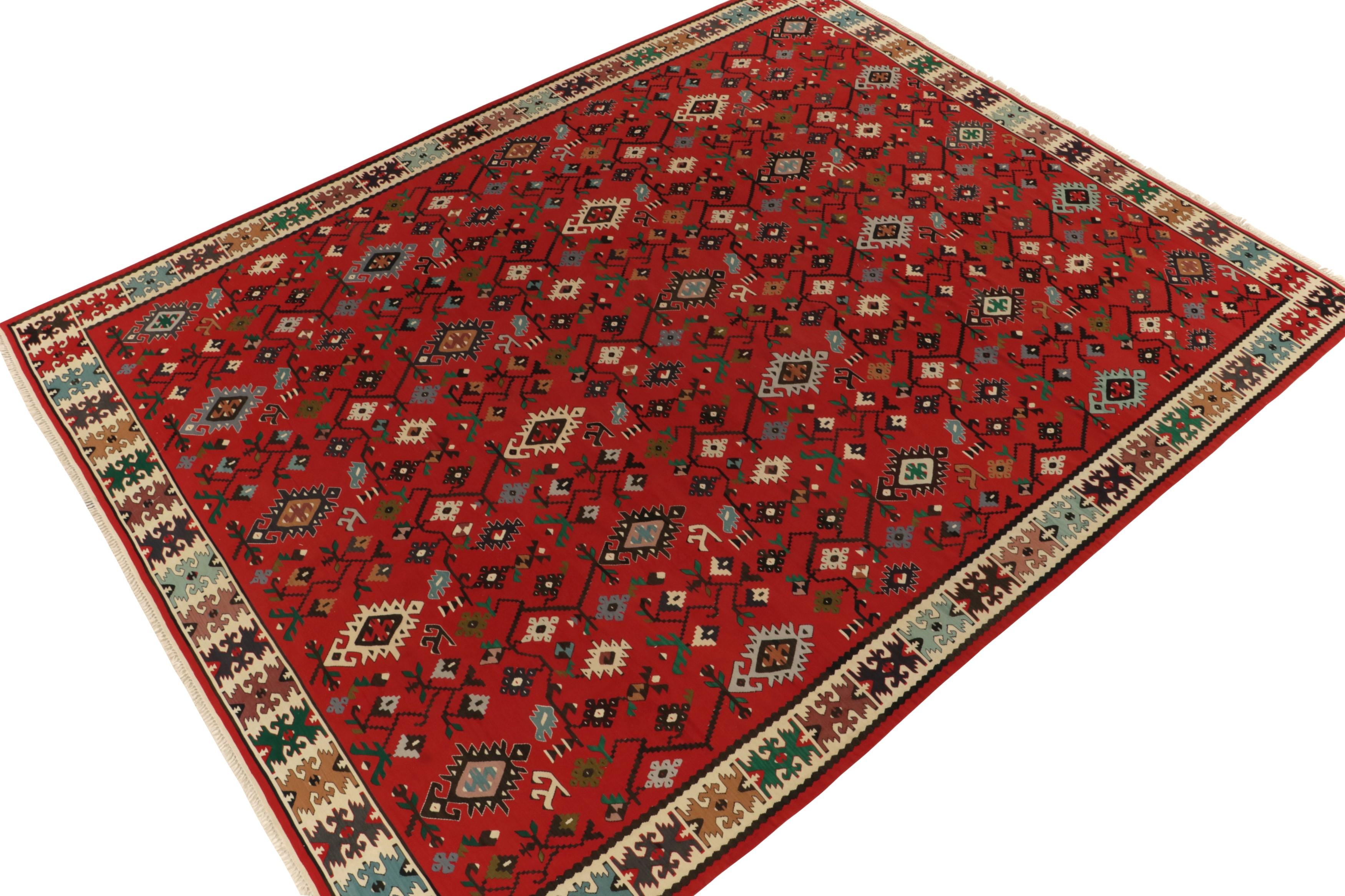Dieser mehr als 80 Jahre alte, zwischen 1920 und 1930 in der Türkei gefertigte antike Kelim-Teppich bietet ein exquisites, ausgewogenes Medley aus Spektral- und Pastellfarben mit einem satten roten Hintergrund. Das geschmackvolle Nebeneinander von