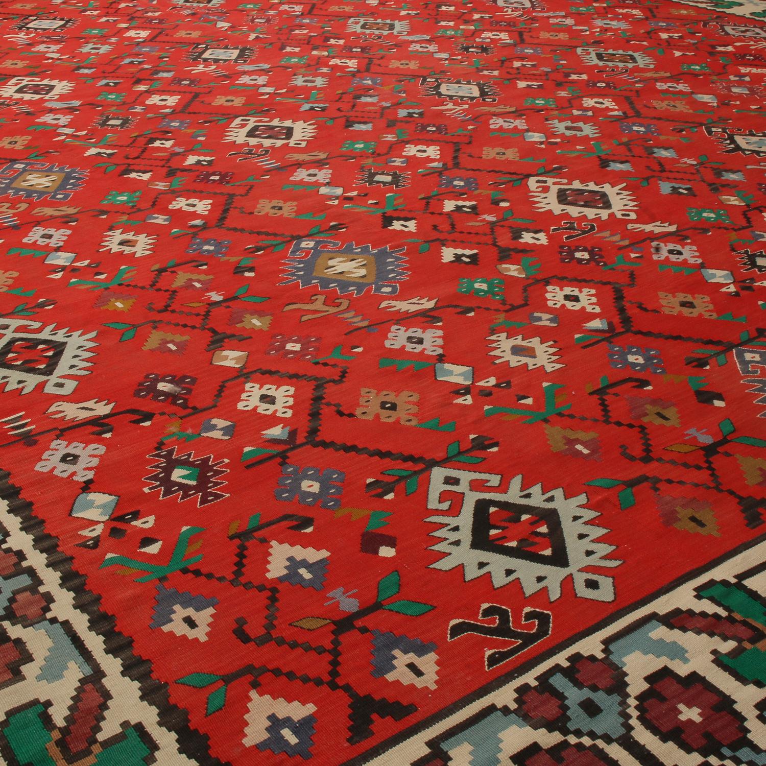 Over 80 years old originating from Turkey between 1920-1930, this antique Kilim rug hosts an exquisite, balanced medley of spectral and pastel colorways with its rich red background. Flat-woven in high-quality wool with naturally dyed yarn in