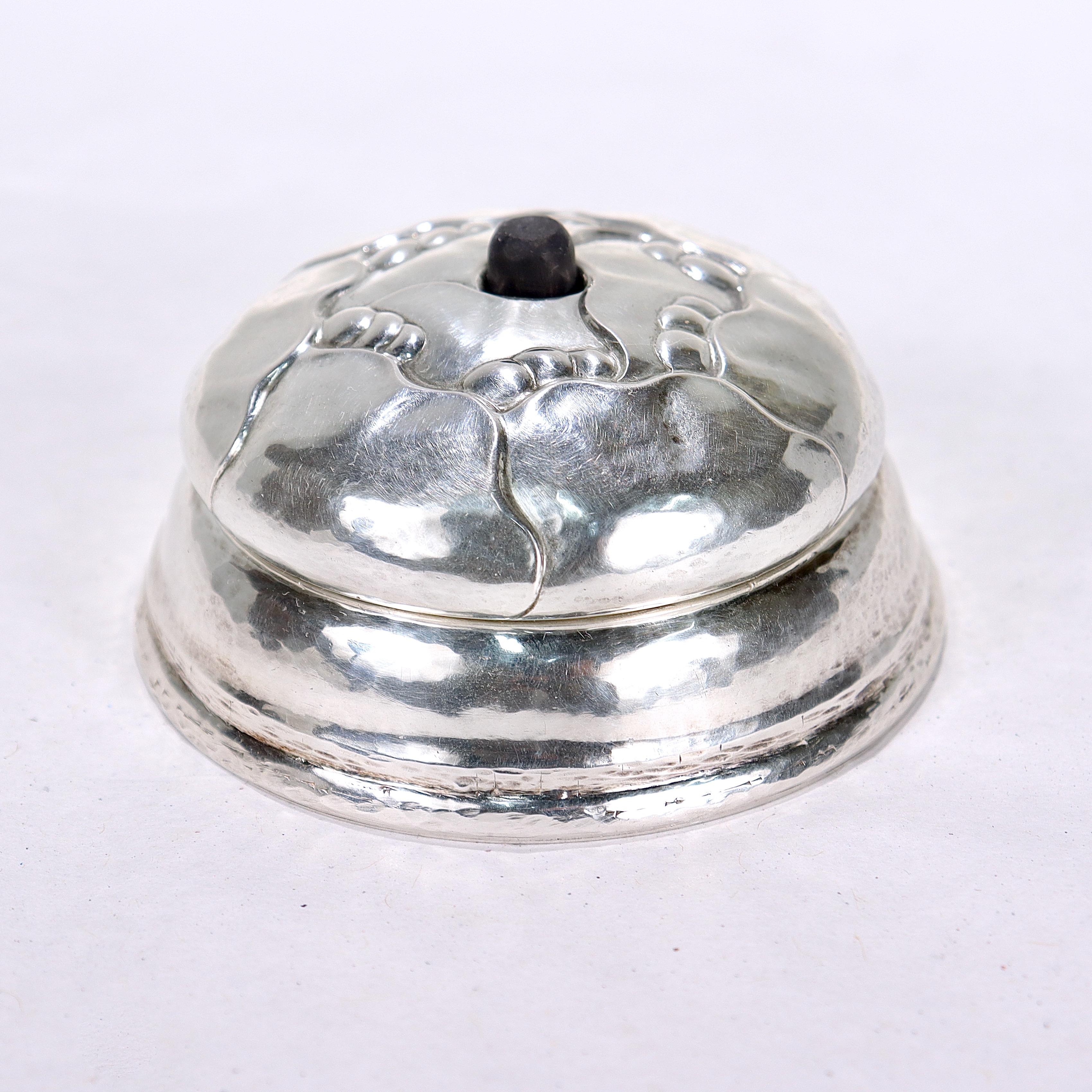 A fine Georg Jensen silver bell push. 

In 830 silver.

Model no. 59.

With floral decoration to the top, hand hammered work to the sides, an associated spring action button to close the circuit, and (apparently) original mechanical