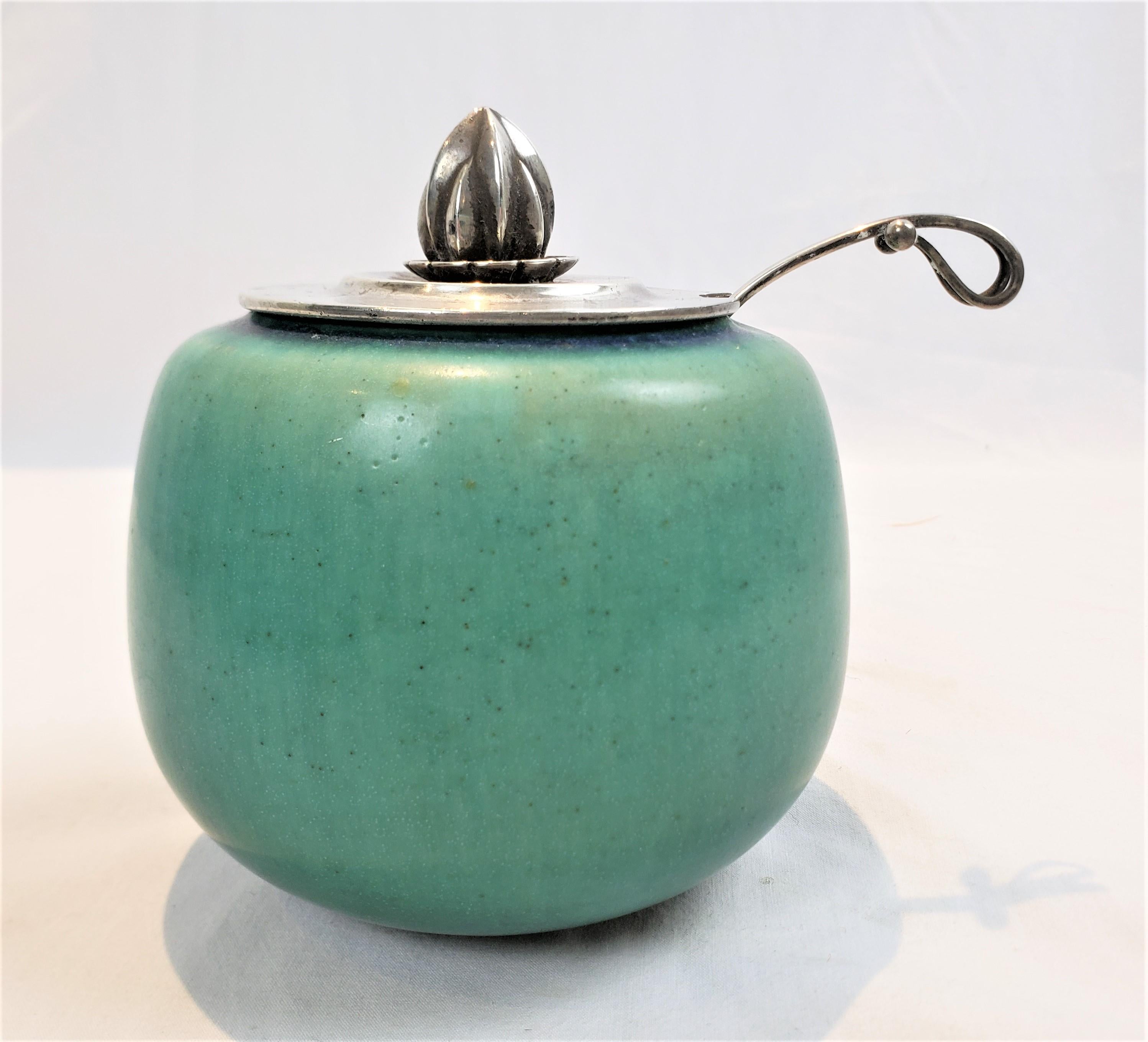 This jam jar or pot was made by the iconic Georg Jensen of Denmark in approximately 1920 in the period Art Deco style. The jam pot itself was done by Saxbo pottery factory of Denmark with a turquoise glaze with a matte finish. The lid was designed