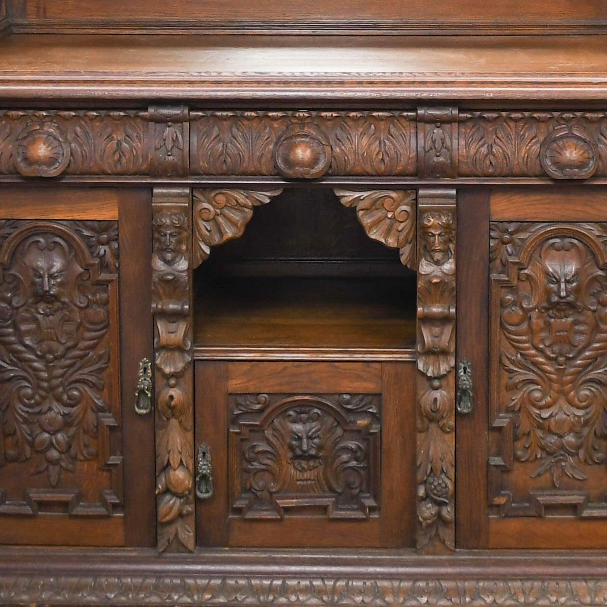 Este Antique George Fleet & Co. El Armario Servidor Buffet de Roble Tallado a Mano es una celebración imponente de la artesanía victoriana y la elegancia del Renacimiento Gótico. Cada centímetro de esta imponente obra maestra está repleto de
