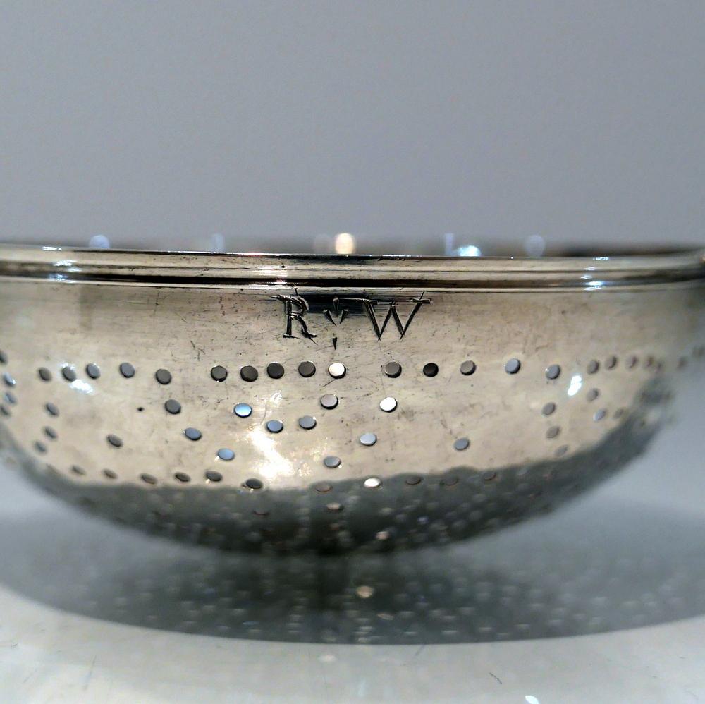 A sweet early Georgian silver lemon strainer decorated with an elegant pierced circular central bowl and two applied stylish handles. There are contemporary initials and crest hand engraved for importance.

Weight: 3.5 troy ounces/109