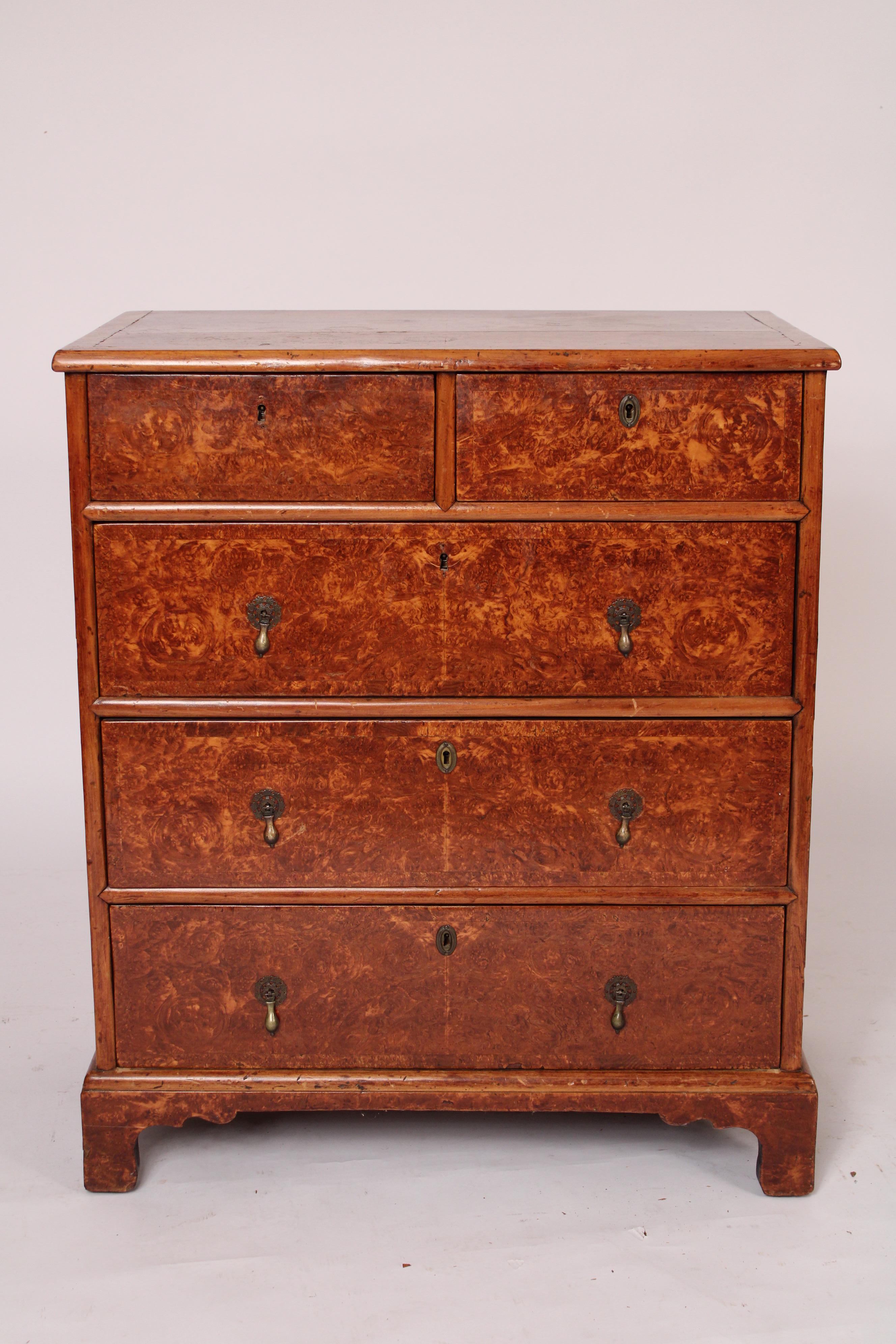 George I style burled wood chest of drawers, circa 1910. With a slightly rectangular top with molded front and side edges, two top drawers over 3 lower drawers all with brass tear drop pulls, a molded base resting on bracket feet. The burled wood is