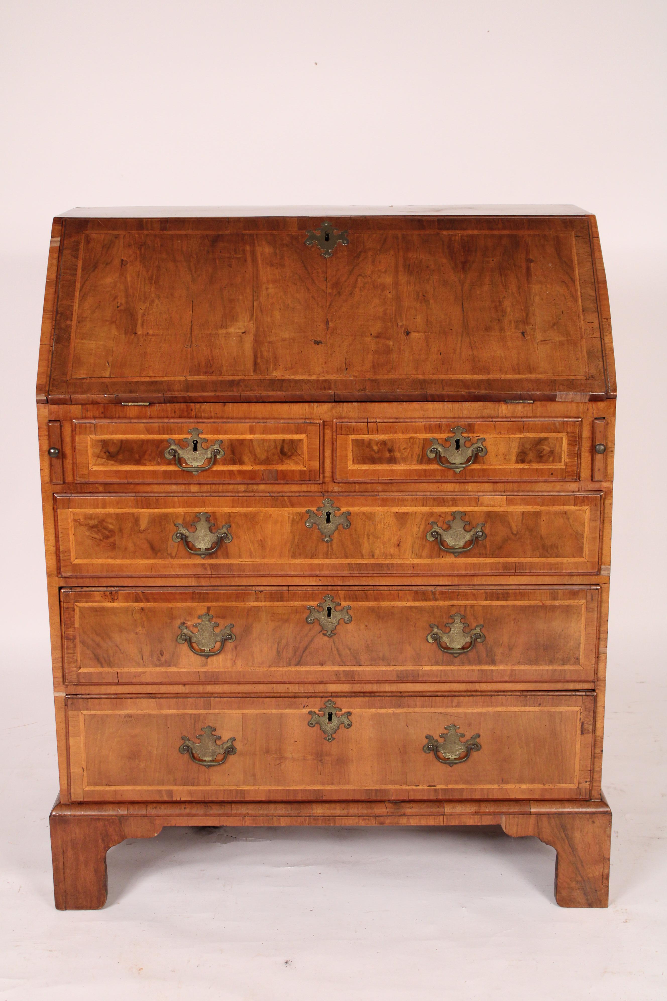 Antique George I style walnut slant top desk, 19th century. With a walnut slant top with herringbone inlay, interior with prospect door flanked on either side by two drawers and cubby holes, top two drawers and 3 graduated lower drawers all with