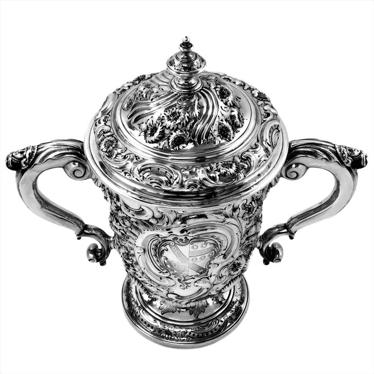 A beautiful Antique Georgian solid Silver Lidded Cup covered in ornate floral chased designs. The Trophy has a shaped cartouche on the one side filled with an engraved armorial. The Cup has a fitted lid with matching chased designs. 

Made in