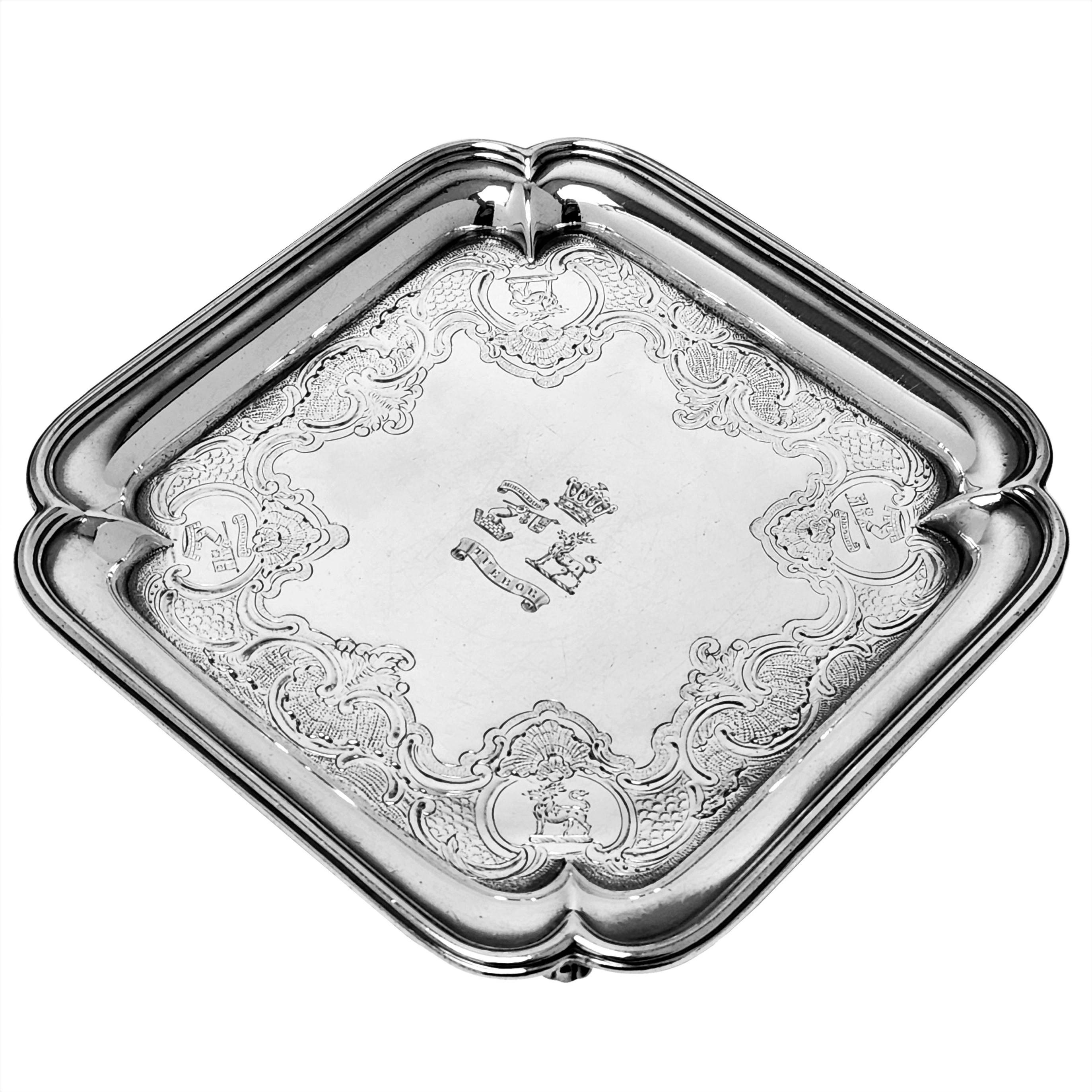 A beautiful Antique George II Sterling Silver Salver by Paul de Lamerie. This de Lamerie Silver Waiter has a square form with rounded corners and stands on four scroll feet. The Salver is embellished with an ornate engraved border with a crest