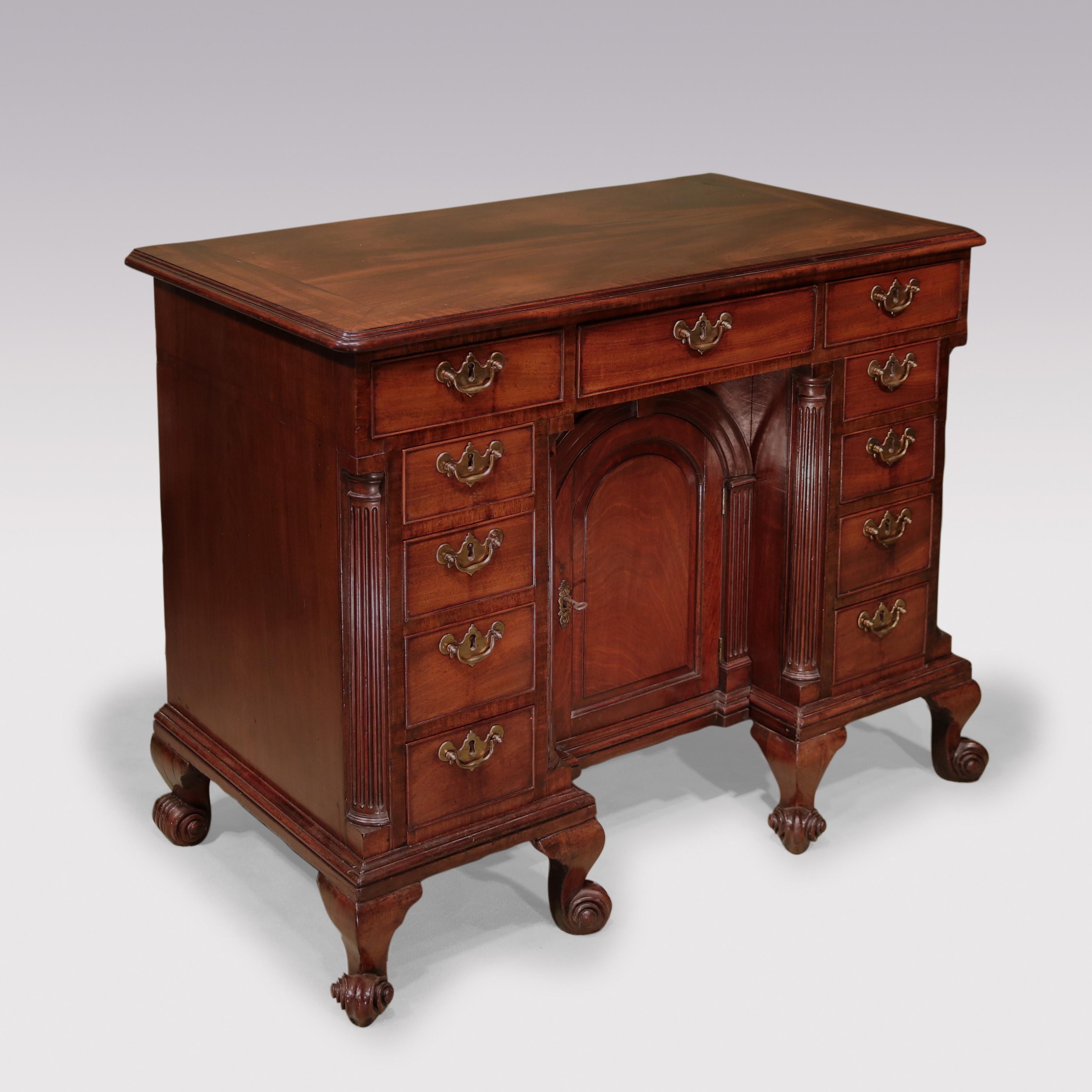 A fine George II period figured mahogany Kneehole Chest, having moulded edged crossbanded cleated top above various drawers retaining original brass backplate handles.  The piece with column corners, having central sliding arched cupboard door
