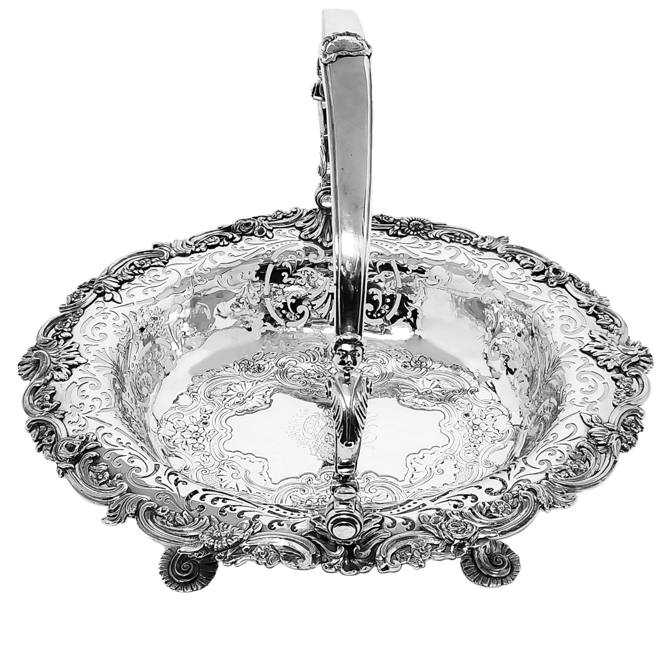 A magnificent Antique George II Sterling Silver Swing Handled Basket with an oval form standing on four shaped feet with bacchanalian faces at the capital of each foot. The Basket has an ornate chased floral & scroll pattern border and an elegant