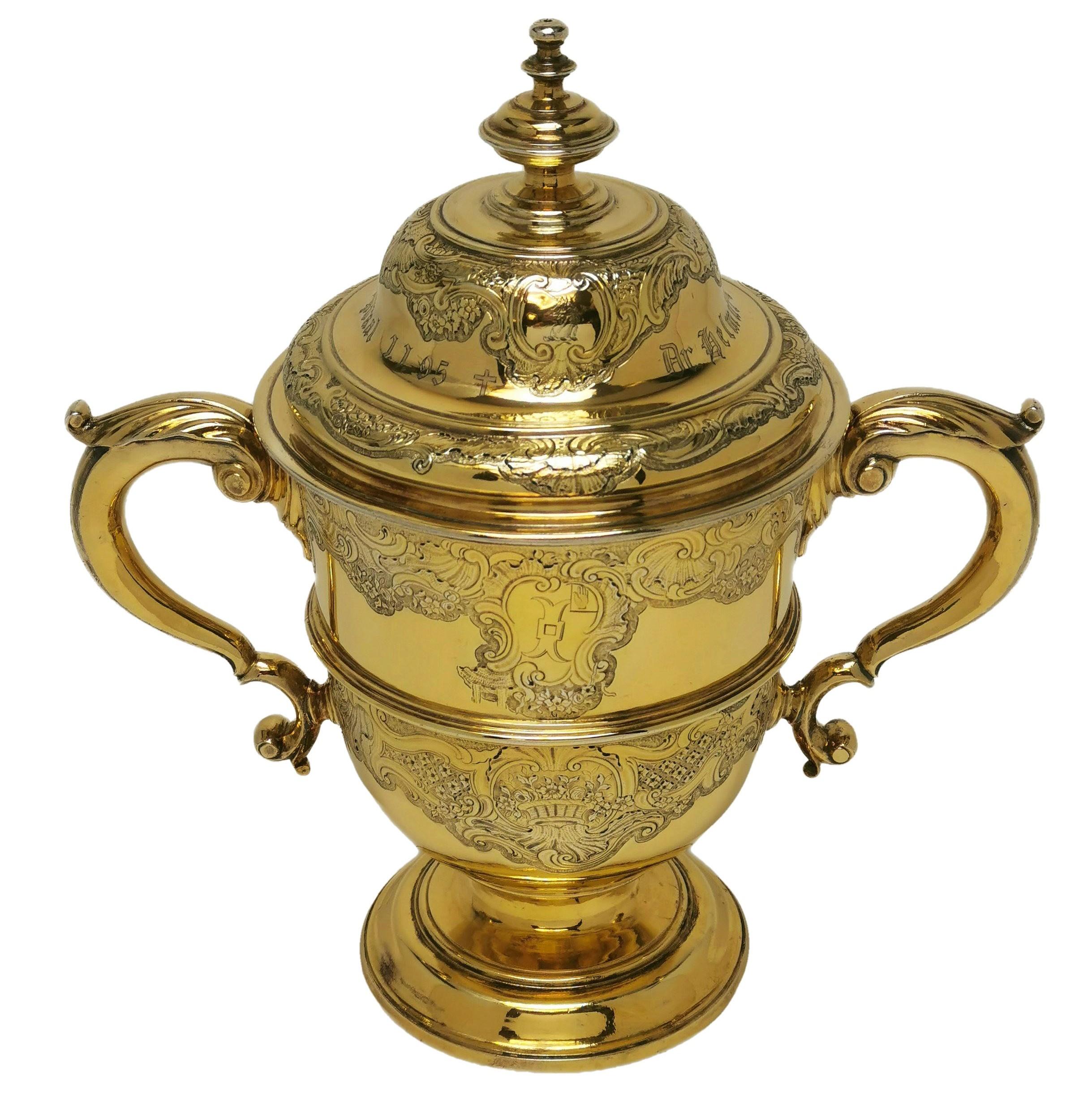 A beautiful Antique George II Silver Gilt Cup and Cover embellished with delicate, ornate Rococo style engravings on the body of the Cup and on the domed lid. The Body of the Cup has a cartouche on each side and each features an engraved crest. The