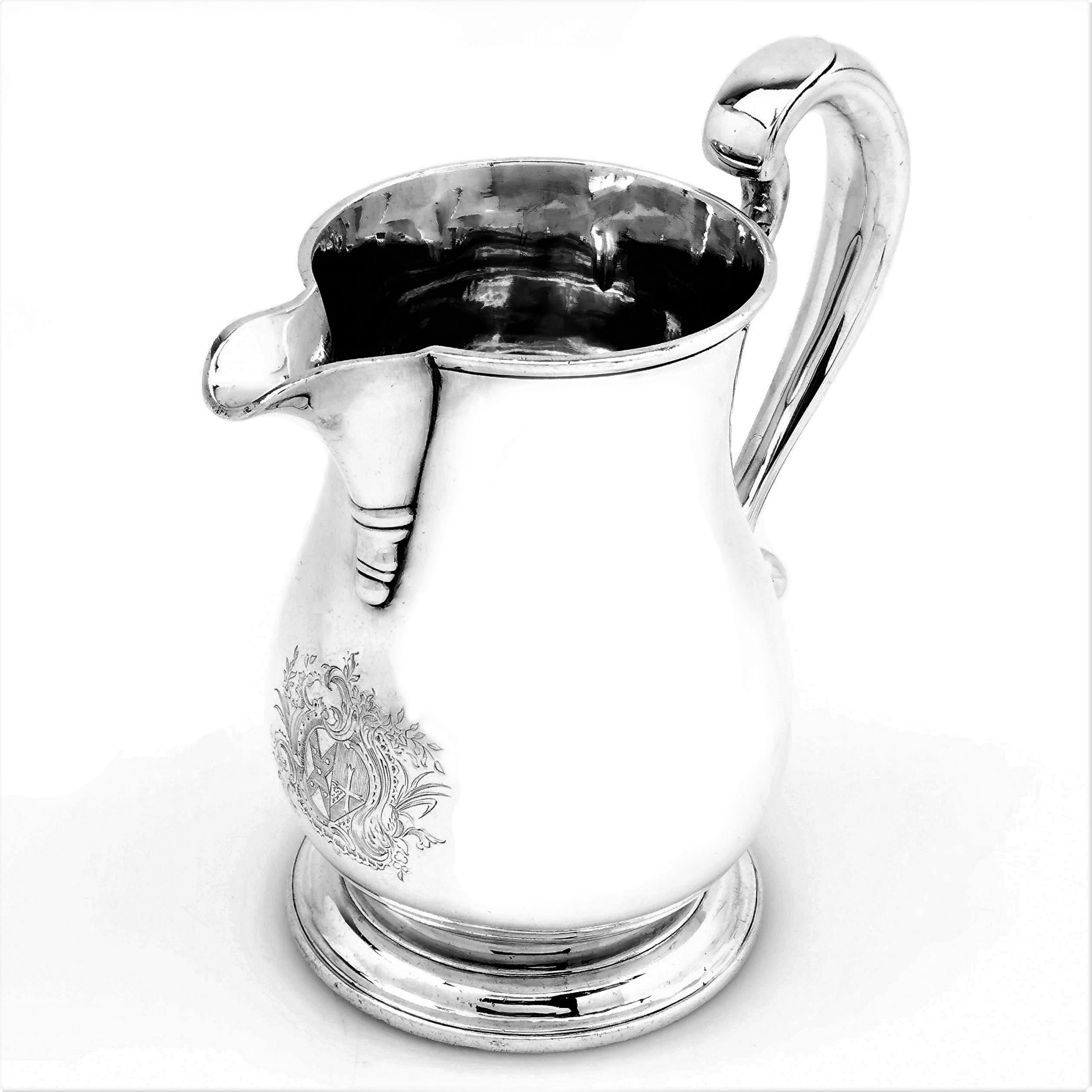 An antique George II Sterling Silver Jug in a Classic baluster shape. The Jug stands on a low spread food and has an impressive scroll handle. This Georgian Jug has a large silver crest engraved opposite the handle.

Made in London in 1762 by Thomas