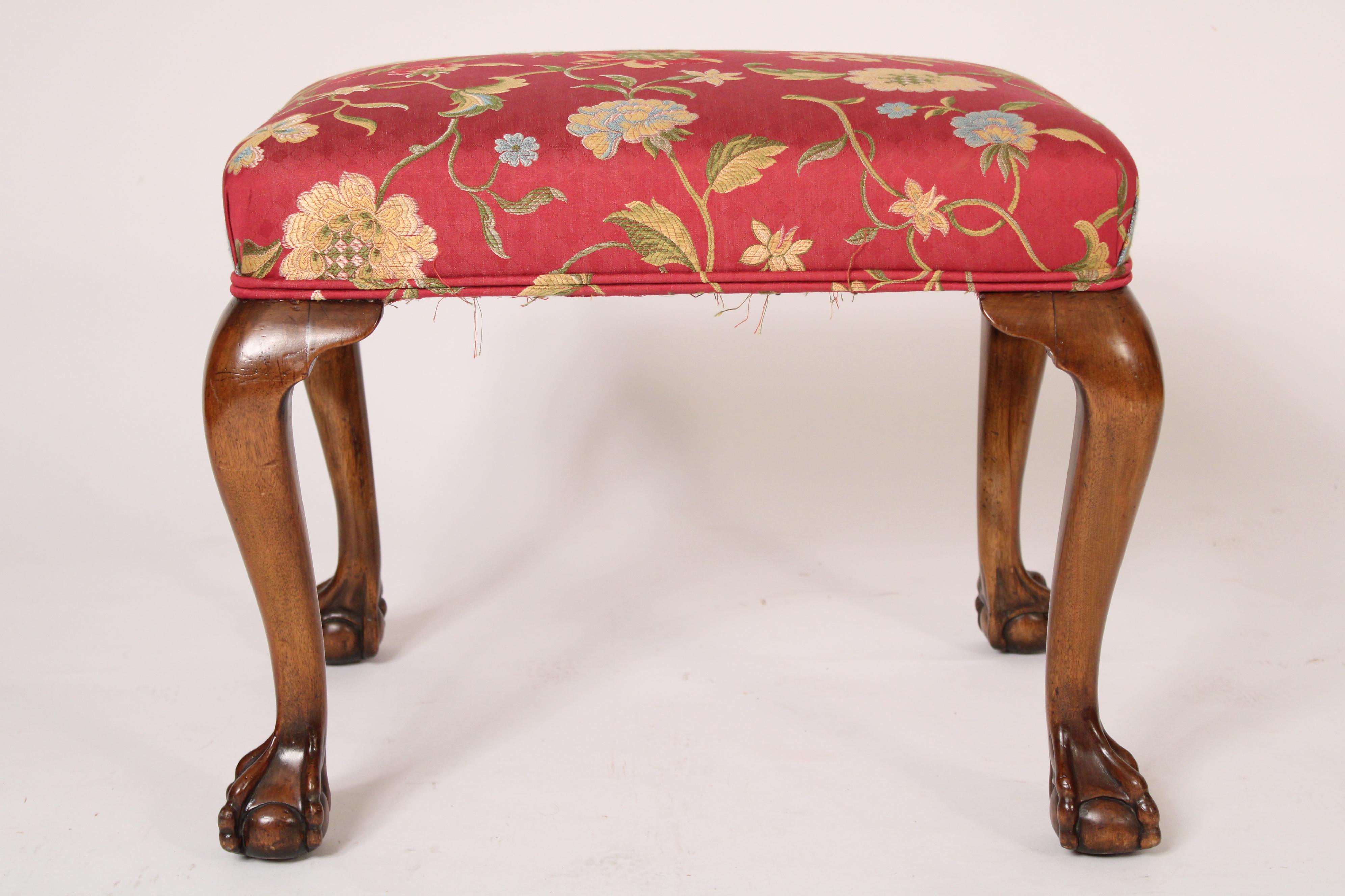 Banc ancien en acajou de style George II, fin du 19e siècle. L'assise, récemment tapissée de motifs floraux, repose sur des pieds cabriole terminés par des pieds boule et griffe.
