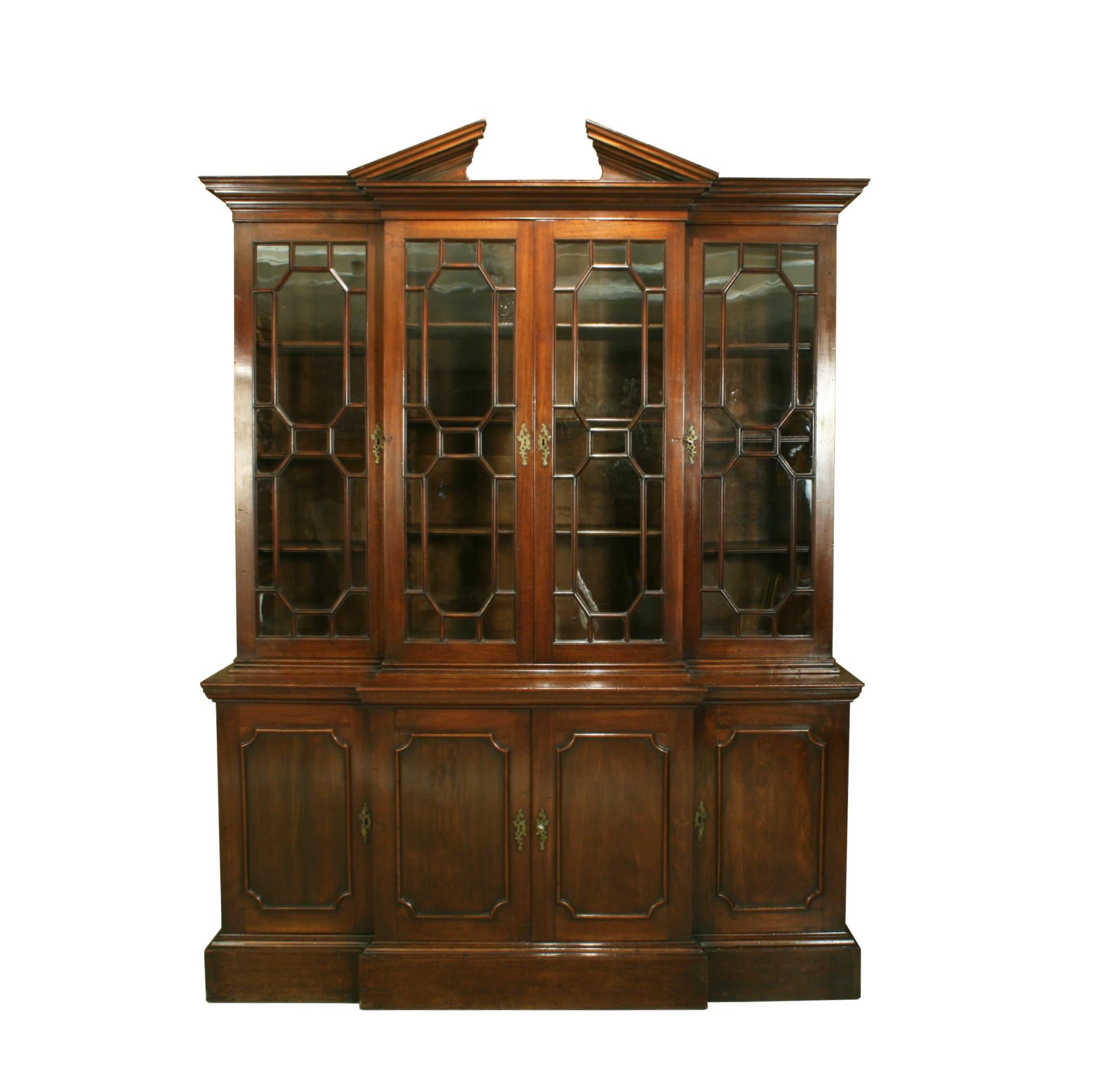 A wonderful Georgian mahogany breakfront bookcase of small proportions with astragal glazed doors and broken architectural pediment cornice, 18th century. The upper part with original adjustable shelves. The base fitted with some drawers and