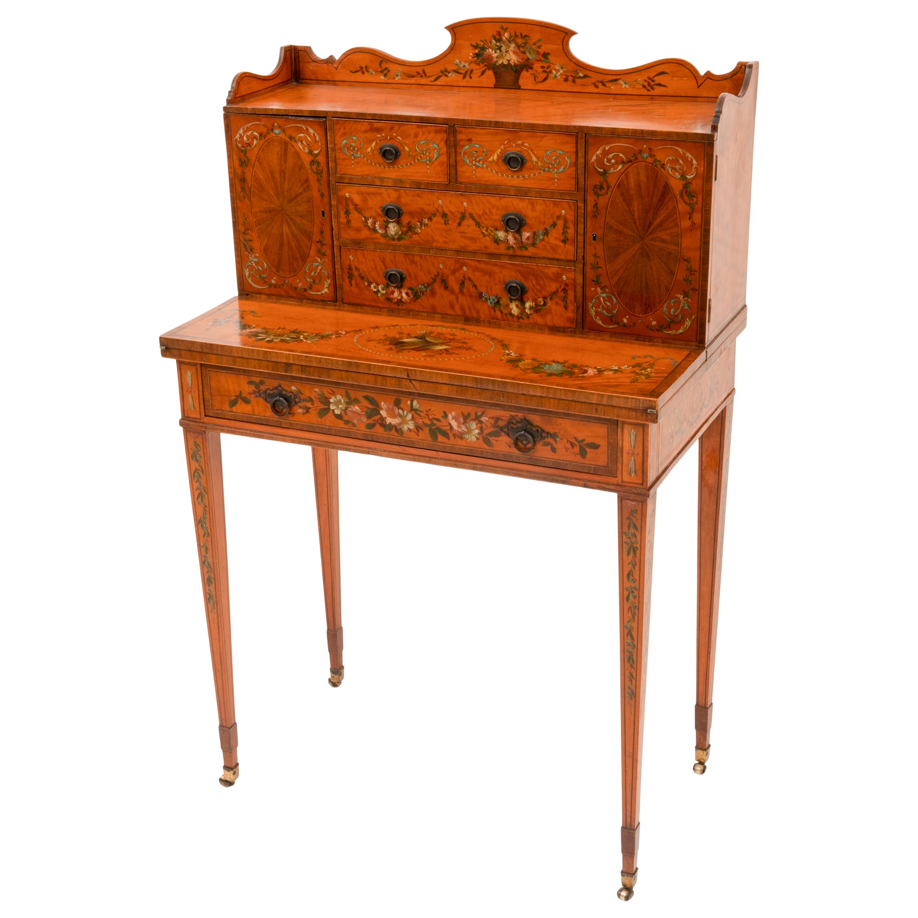A fine antique Edwardian George III Adam Style Satinwood and marquetry paint decorated Bonheur du Jour, desk, attributed to Edwards & Roberts, circa 1890.
The desk with a shaped gallery paint decorated with a floral basket, the back of the desk