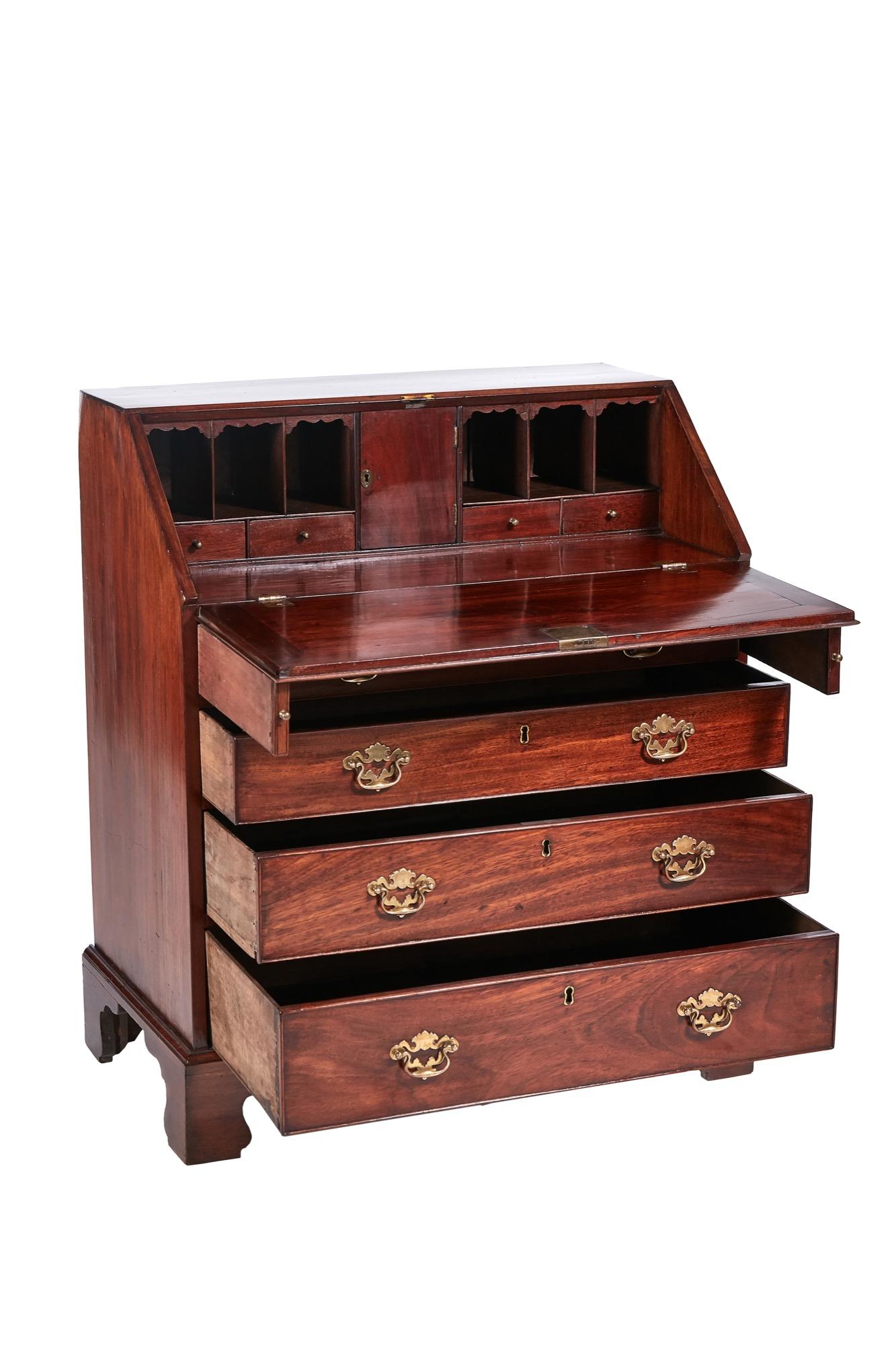 Antique George III mahogany bureau having a sloping fall which opens to reveal a fitted interior of short drawers, pigeon holes and a center door. It boasts four long graduated drawers below and it stands on original bracket feet.

Striking color