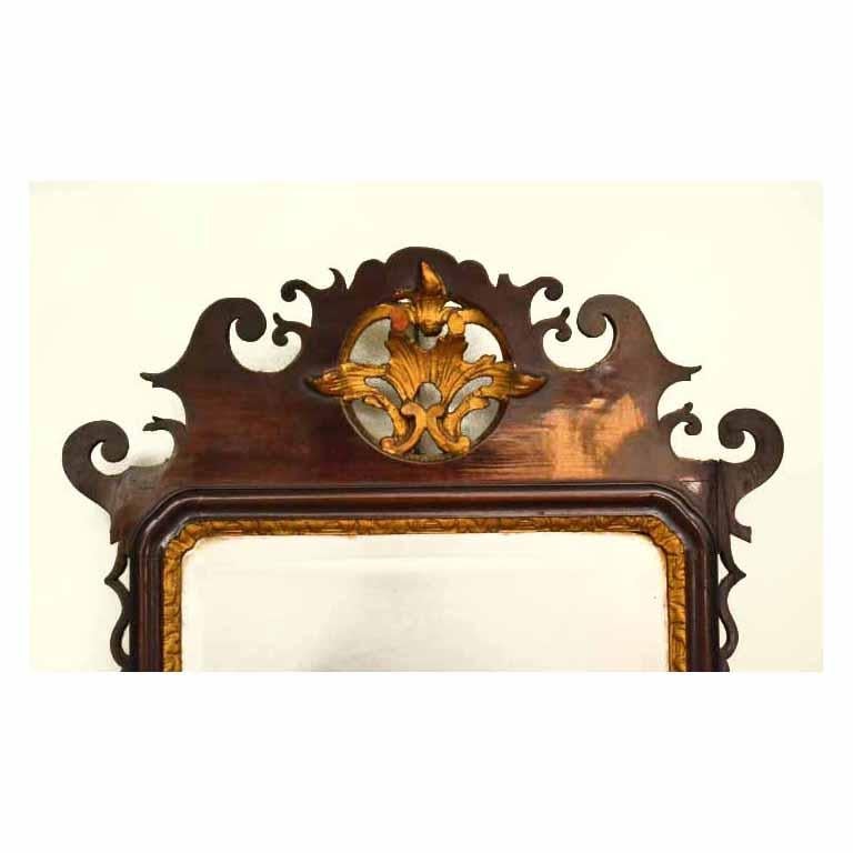 This is a beautiful antique George III mahogany parcel gilt wall mirror, circa 1780 in date. 

The mirror has got a beautiful mahogany frame with carved scrolling  surmounted by a pierced gilt foliate motif with bevelled plate below. 

It is a
