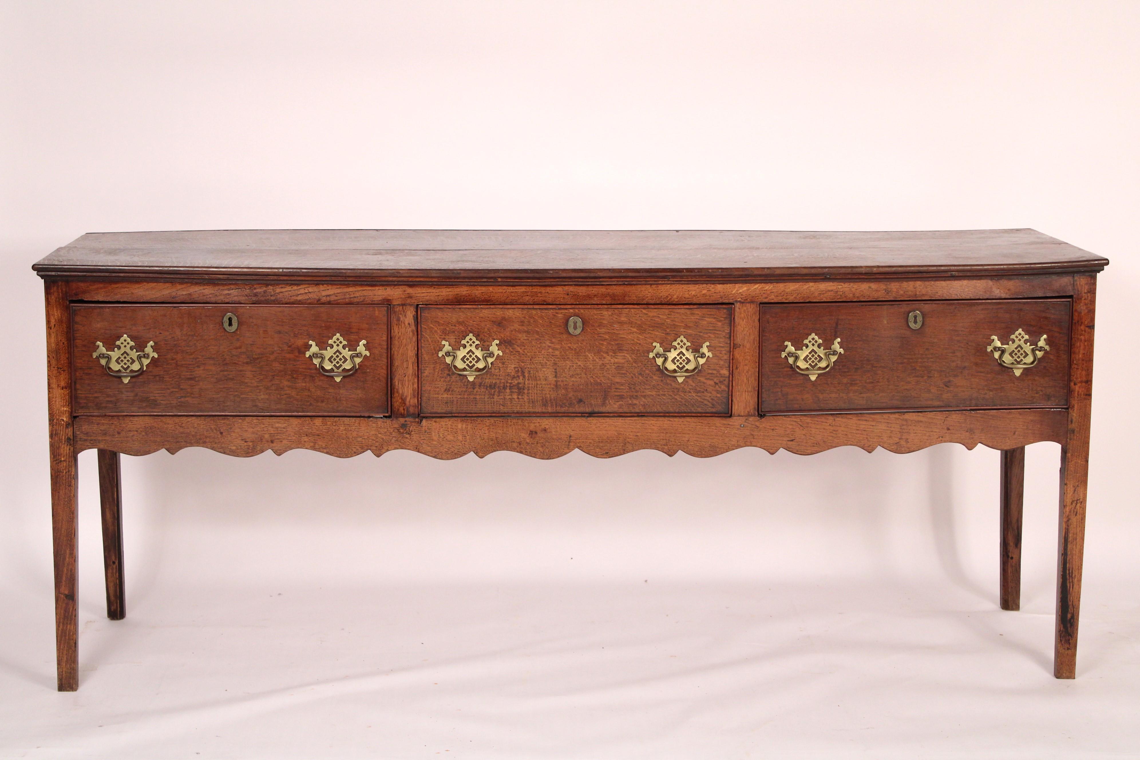 George III oak sideboard, early 19th century. With a rectangular two board top, 3 frieze drawers with later brass hardware, resting on square tapered legs. Hand dove tailed drawer construction. Nice old color.