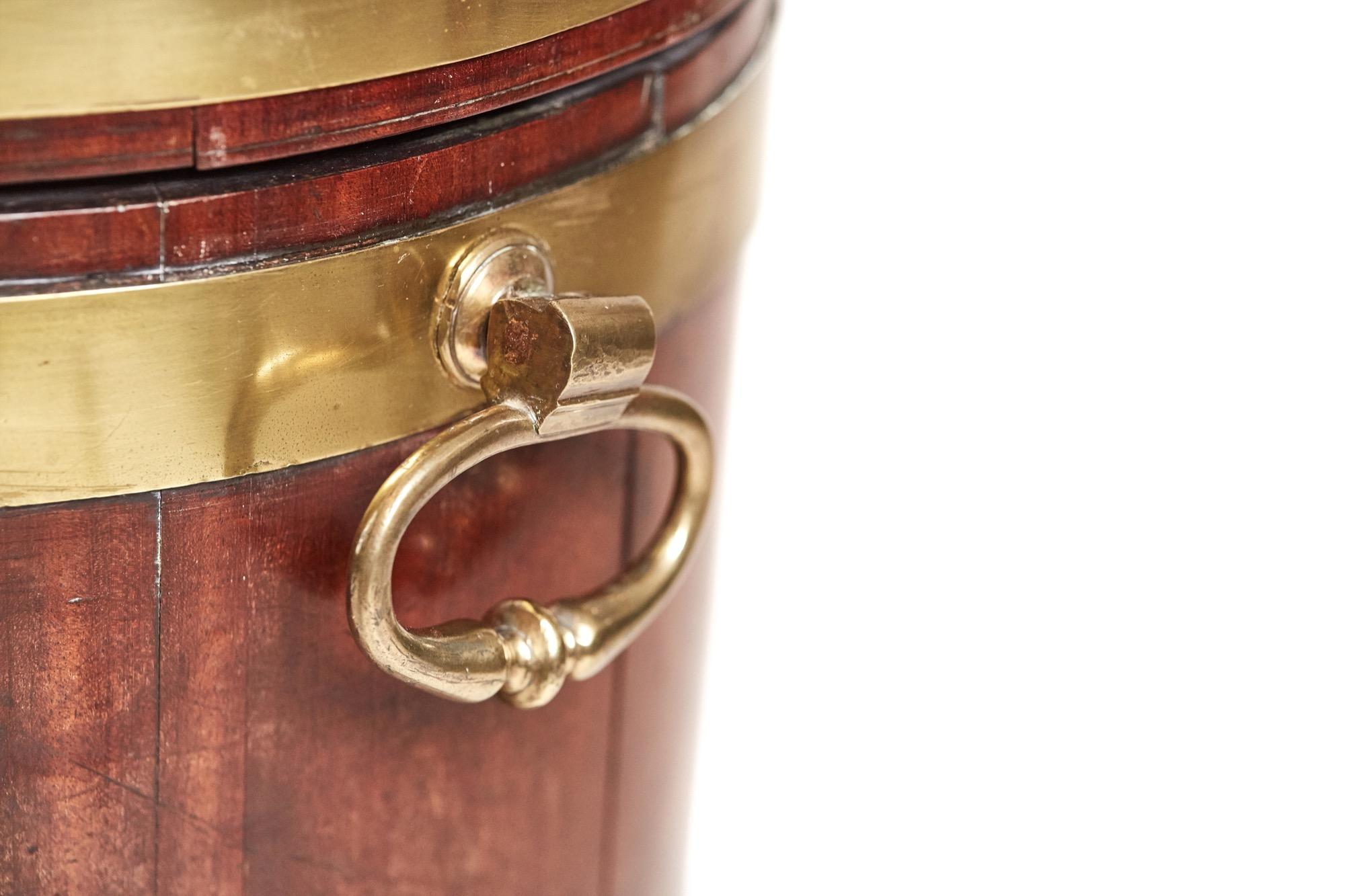 Magnificent antique George III oval mahogany brass bound wine cooler having the original lead lined interior, three original oval brass bands, original brass handles and supported by four out swept legs with original castors.

A rare example in