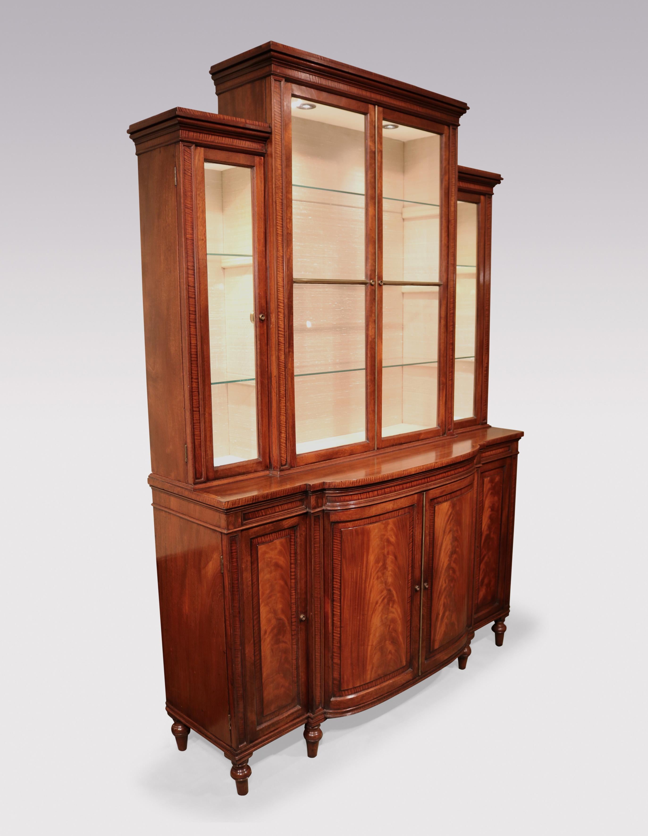 A fine quality George III period mahogany & fiddle back mahogany Display Bookcase of attractive small proportions, having breakfront top section above bow fronted base with plain figured panelled cupboard doors below, supported on short turned